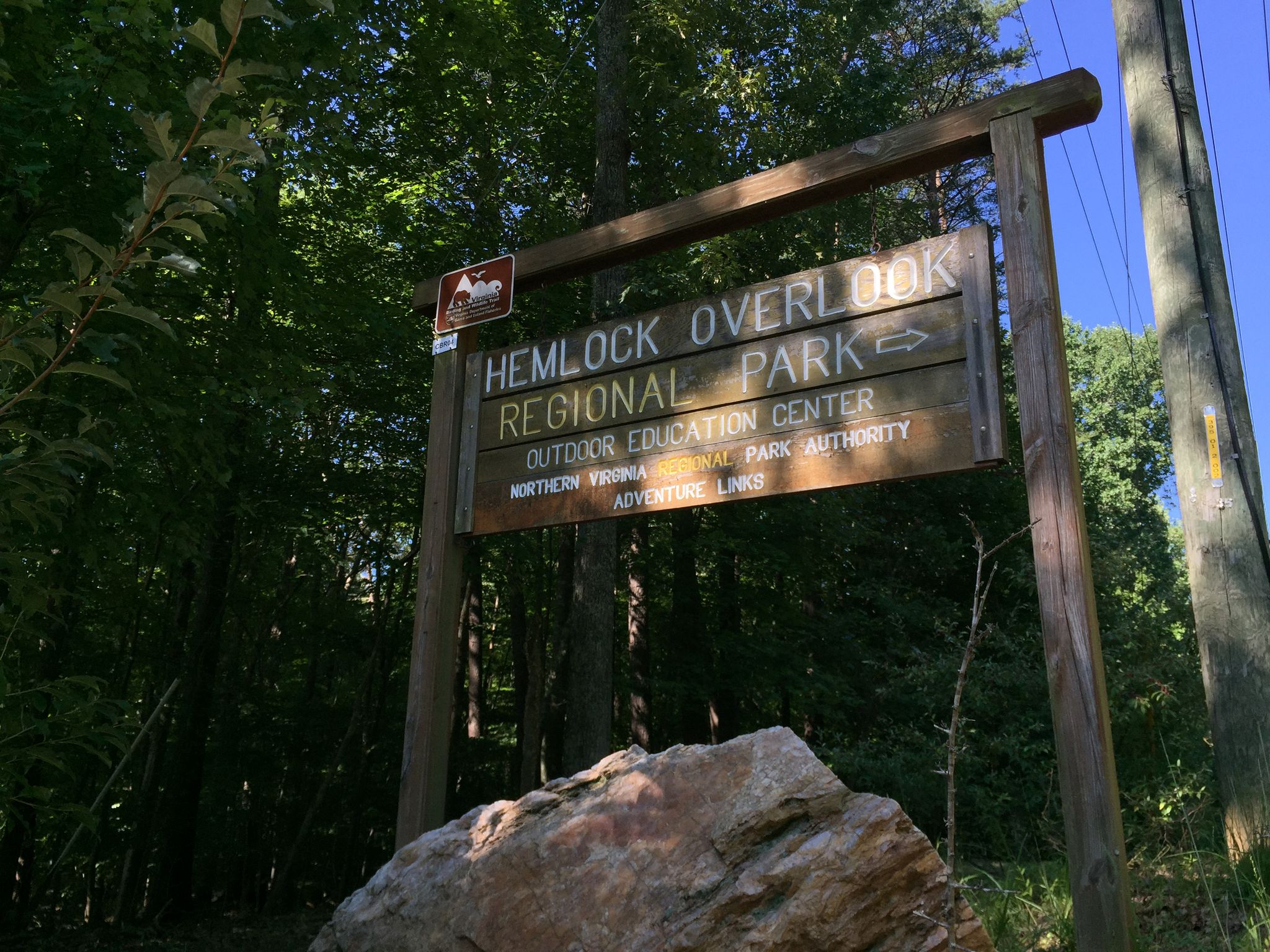 Wooden park sign in a sunlit forest, with a large rock in front. - Bull Run & Hemlock Overlook Regional Parks loop from Manassas, Virginia