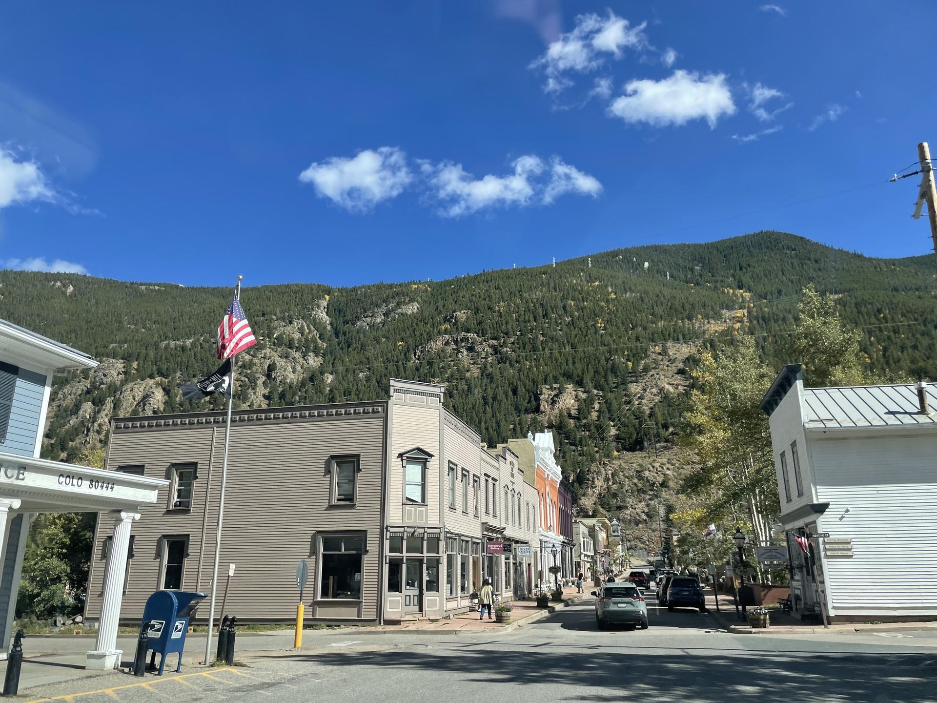 Quaint town street with historic buildings and a large mountain backdrop.