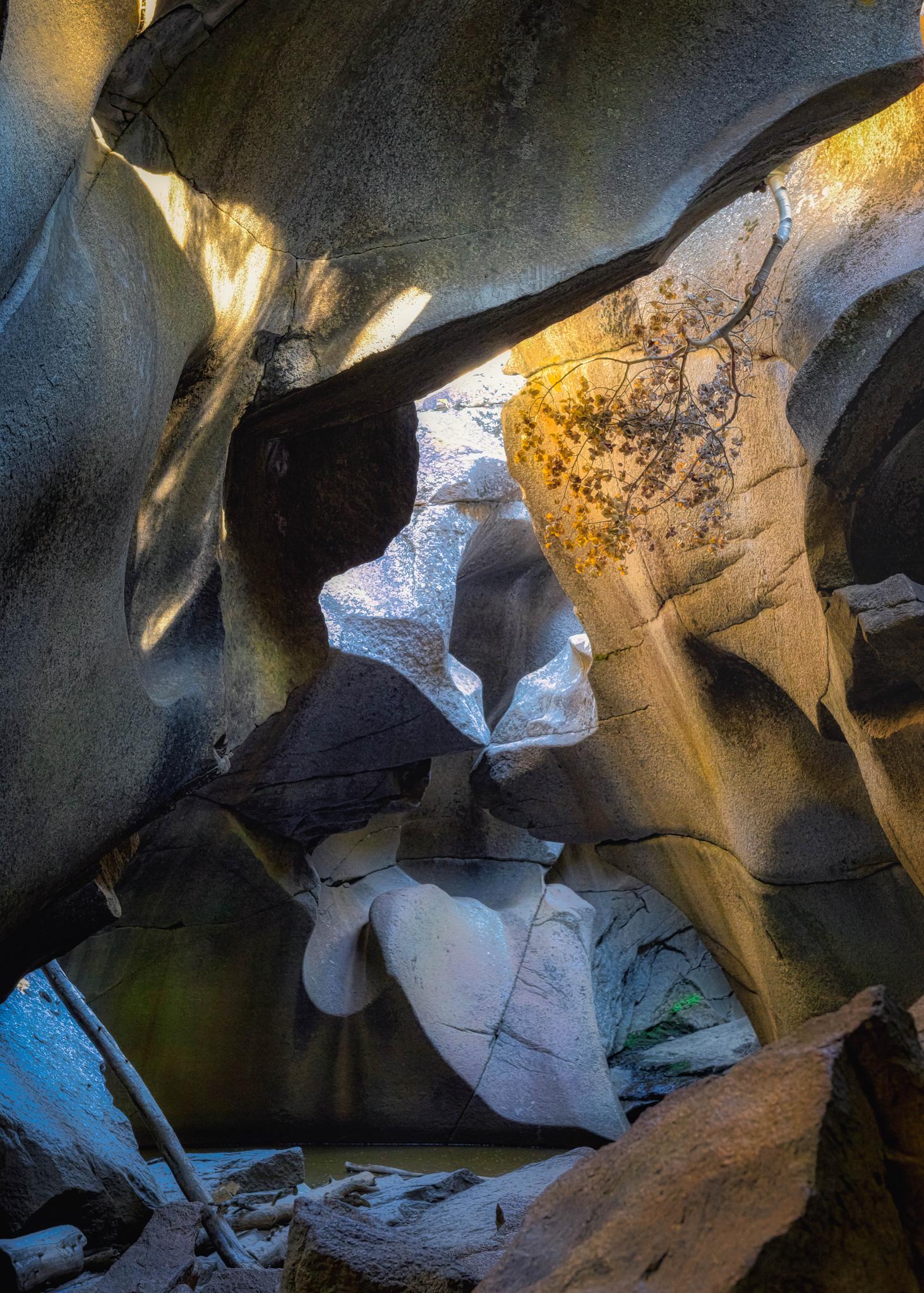 Dramatic light illuminates smooth, sculpted rock formations within a narrow canyon.