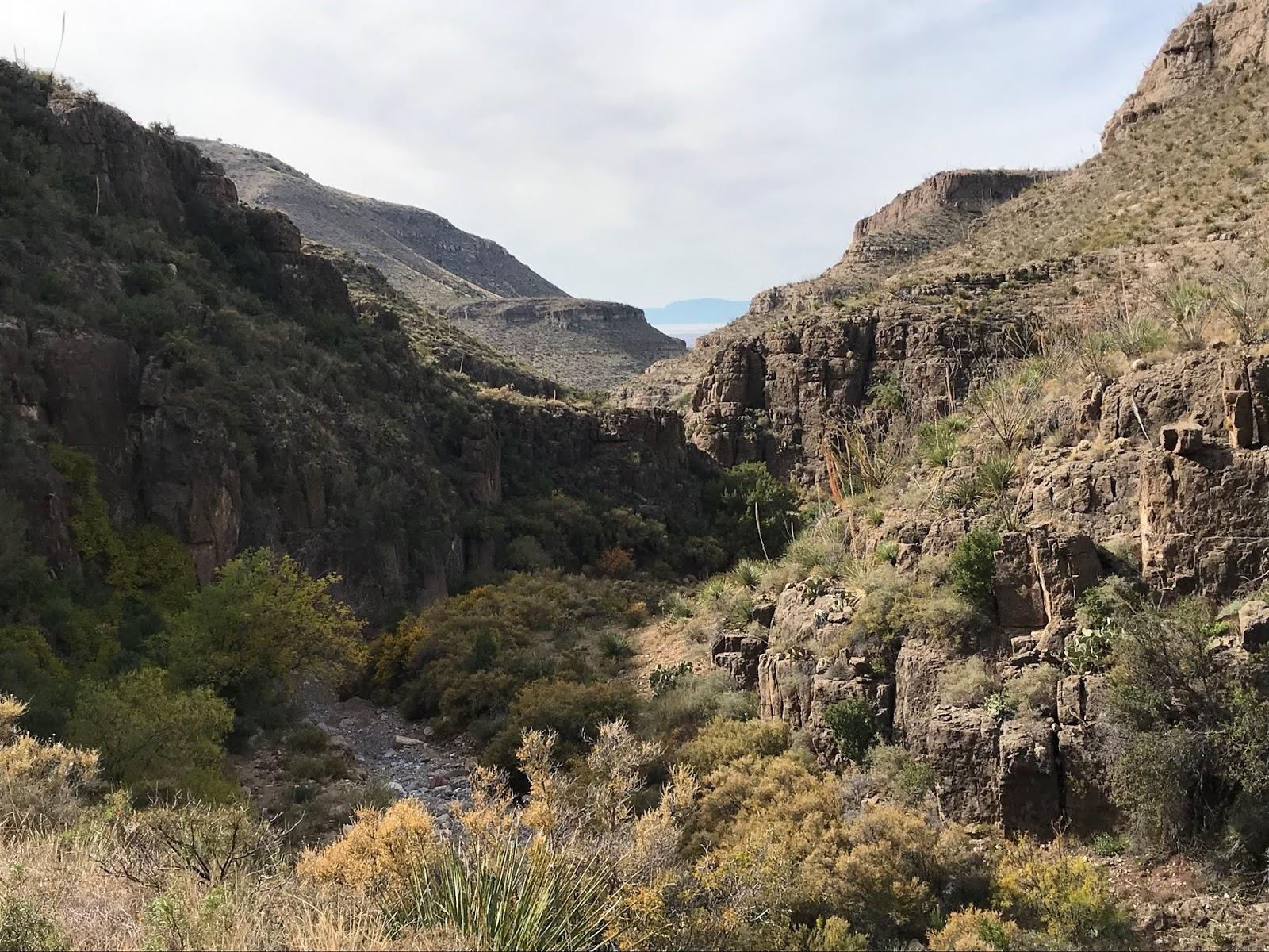 Deep rocky canyon with a dry riverbed and sparse vegetation.