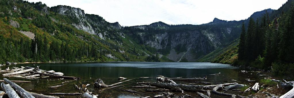 Mountain lake with many floating logs, surrounded by steep, rocky peaks.