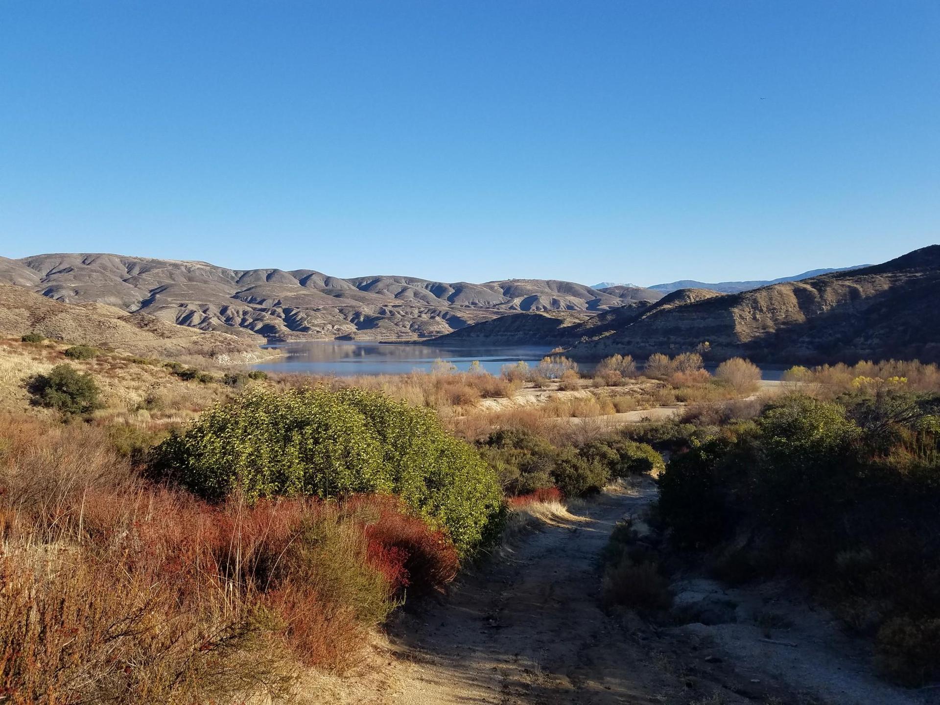 Scenic view of a lake nestled between rolling hills under a clear sky.
