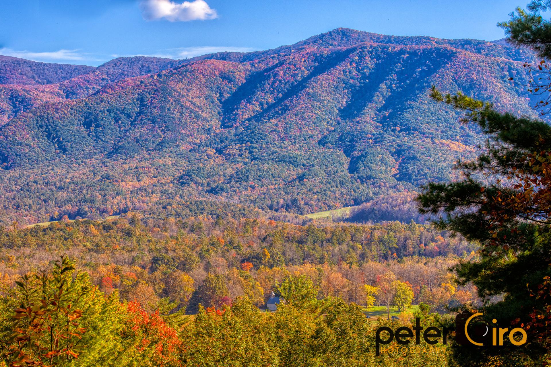 Vibrant autumn mountains with colorful trees under a bright blue sky.