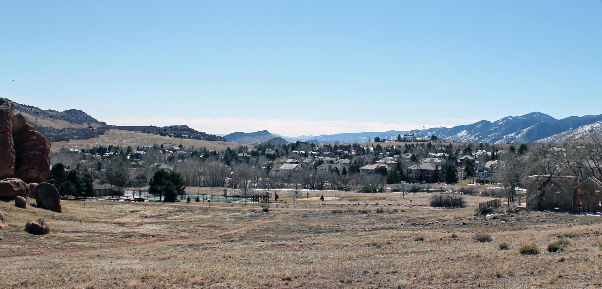 A panoramic view of a town in a valley, surrounded by dry hills and distant mountains.