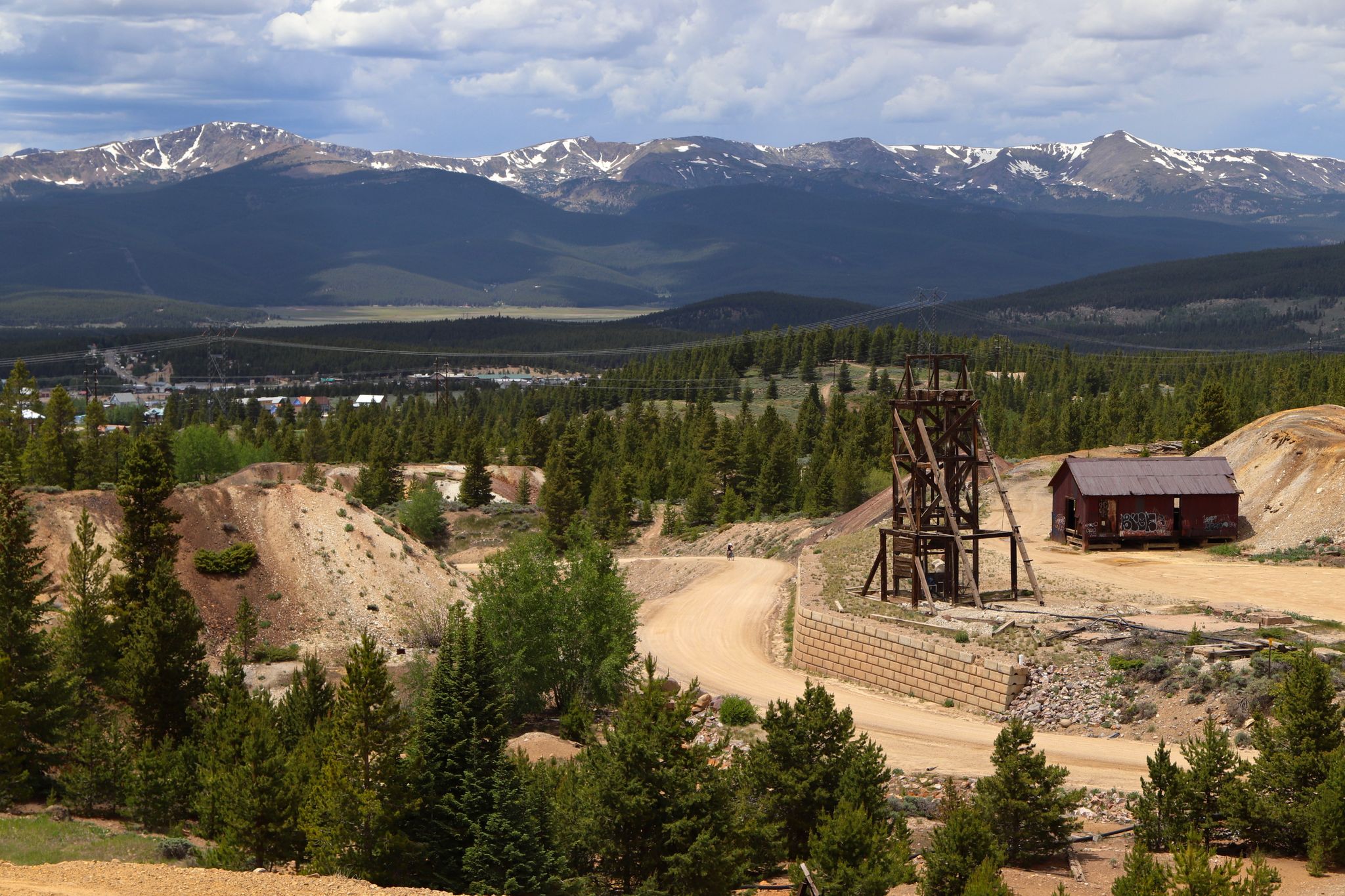 Old mining structure and building in a forested mountain landscape under cloudy skies. - Printer Boy Hill – Rock Hill loop from Leadville