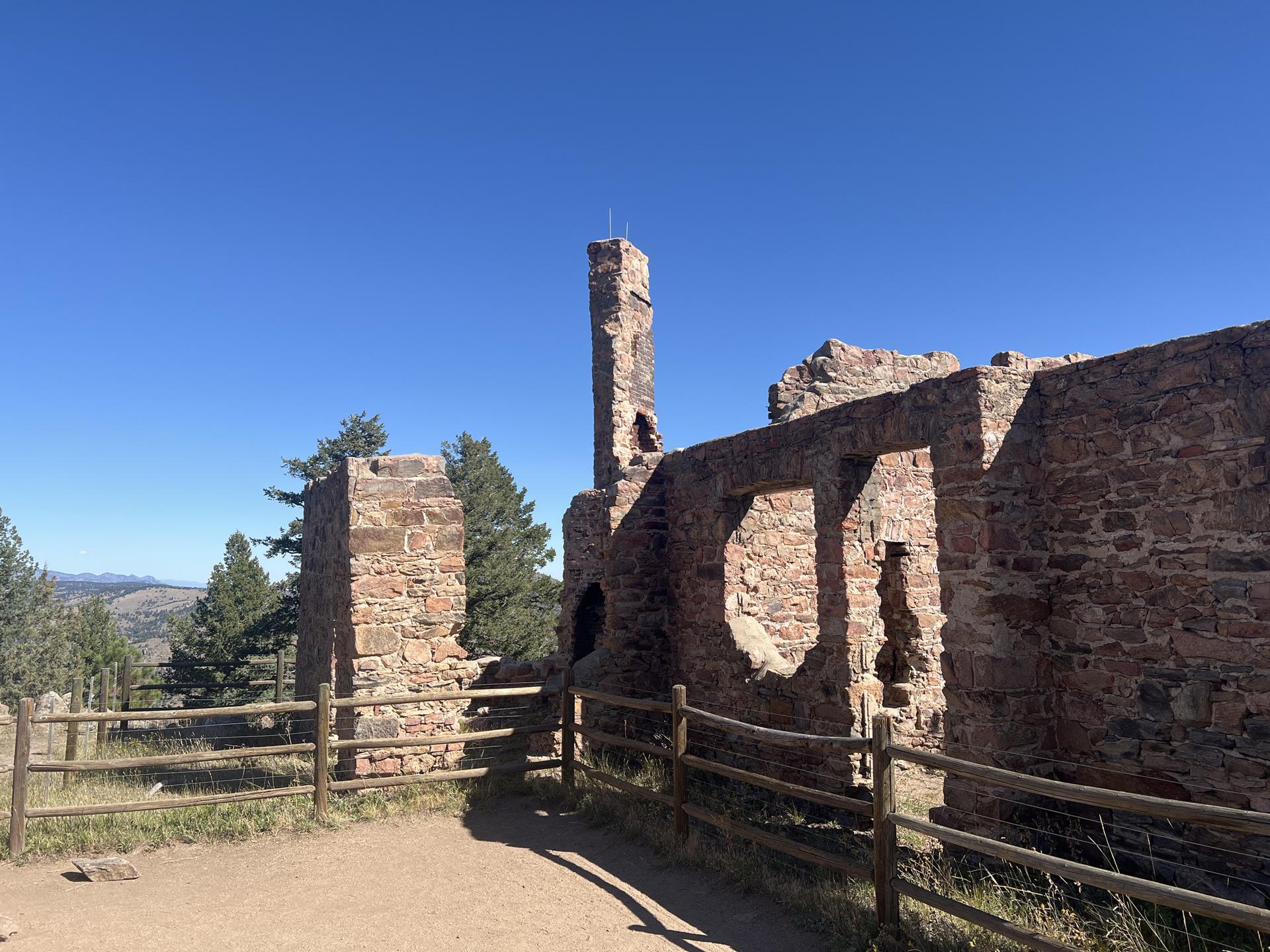 Ancient stone ruins with a tall chimney under a bright blue sky.