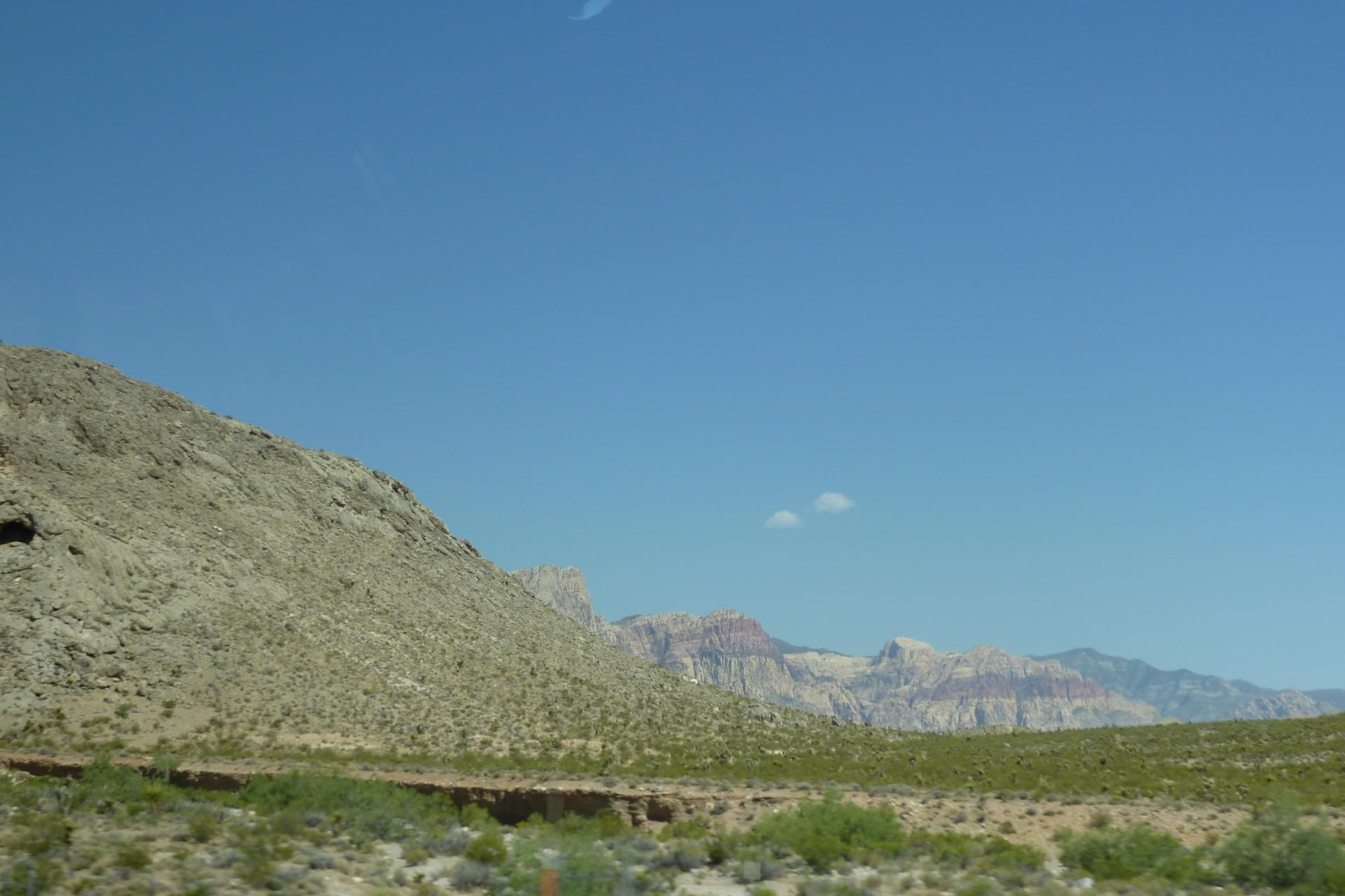 Vast desert landscape with distant mountains under a bright blue sky.