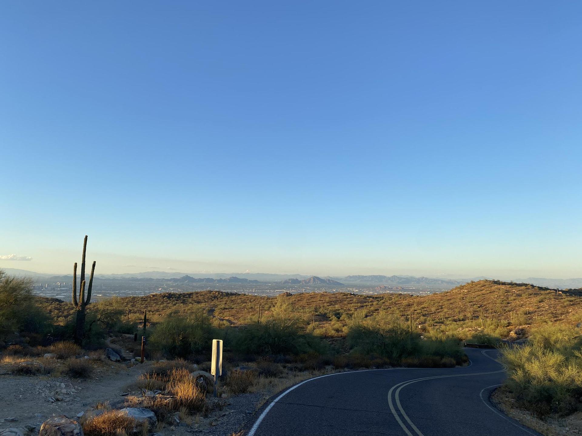 Winding road through desert hills under a clear, golden sky.