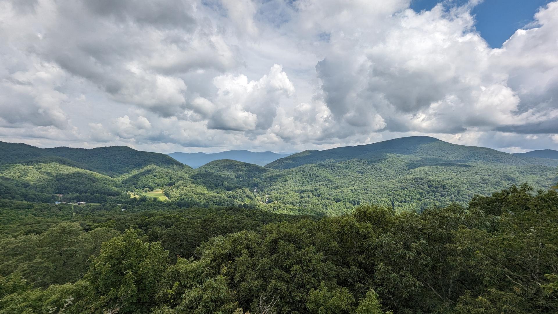 Expansive view of lush green mountains under a dramatic cloudy sky.