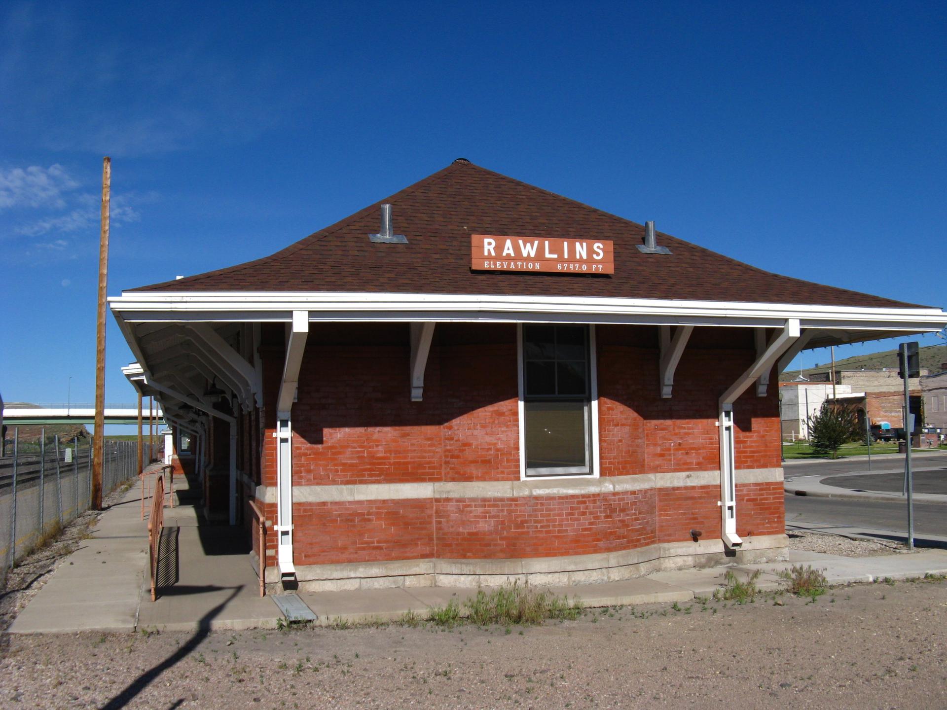 A small, red brick building with a brown roof under a clear blue sky.
