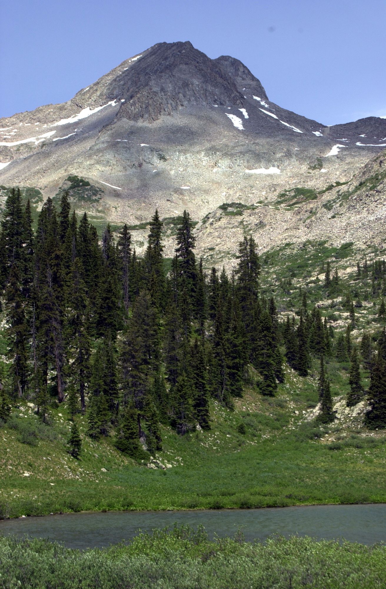 Rocky mountain with snow, evergreen forest, and a calm lake under daylight. - Copper Creek Trail to Copper Lake