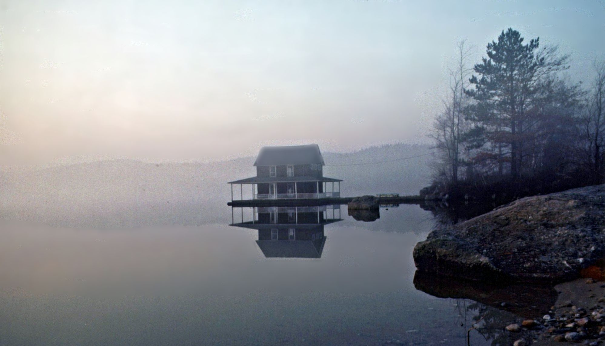 A house on stilts reflects in a misty, calm lake at dawn. - Lake Sunapee & Newport loop from Grantham