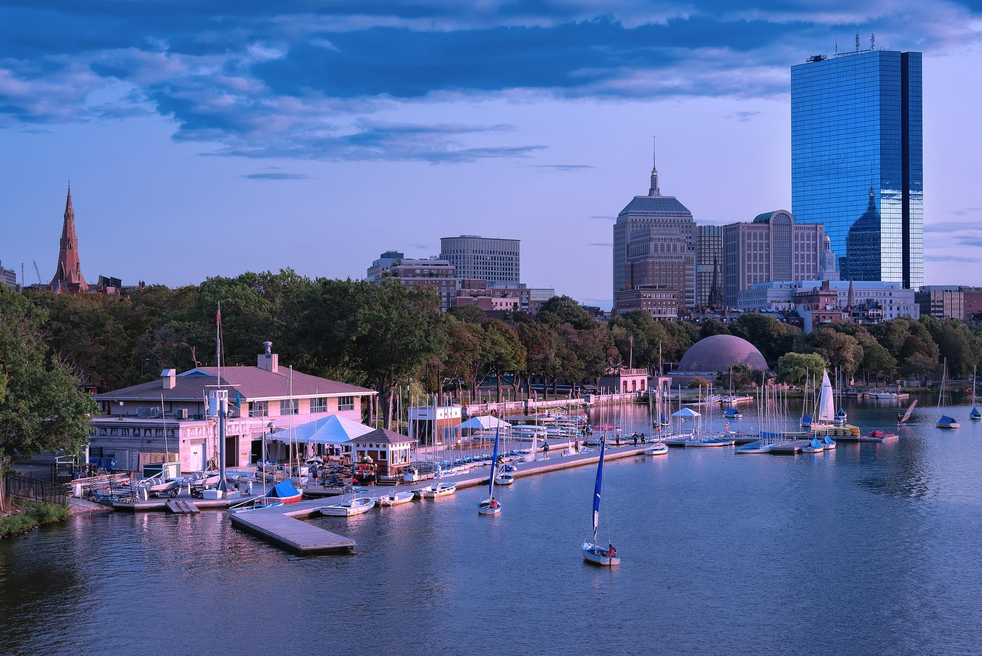 A marina with boats and buildings along a river at dusk.