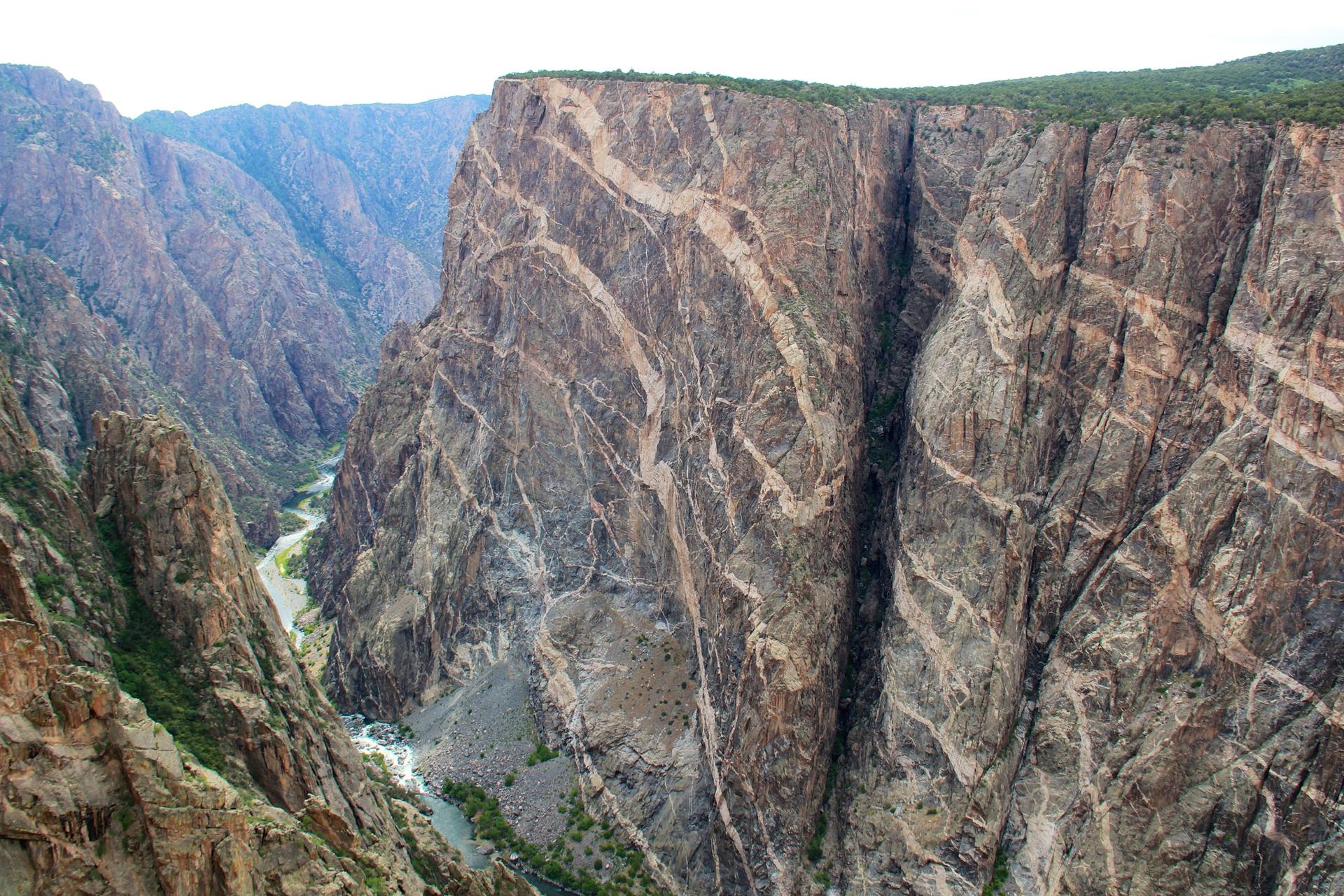 Dramatic view of a deep canyon with intricate rock patterns and a river below.