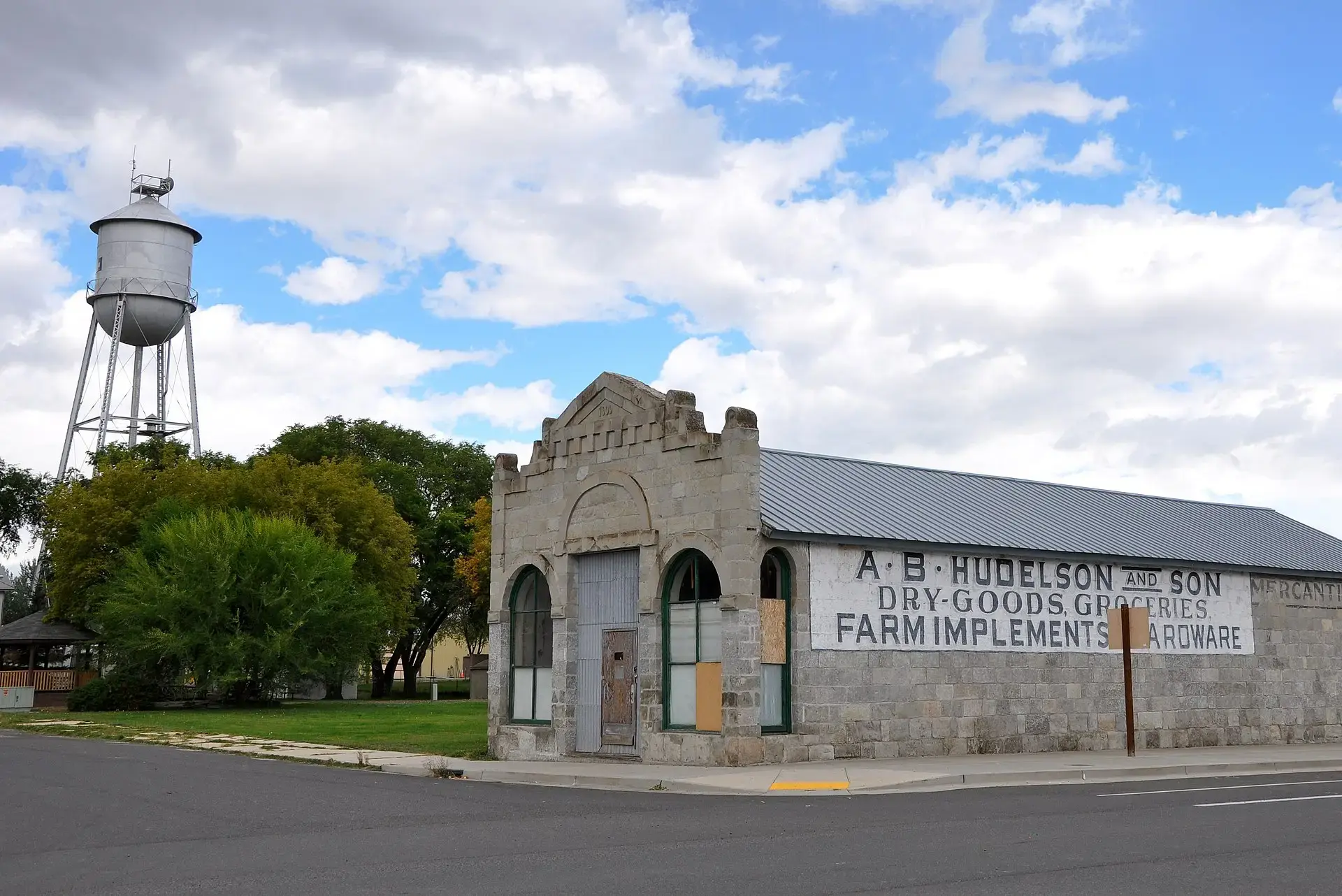 Historic stone building and tall water tower under a partly cloudy sky.