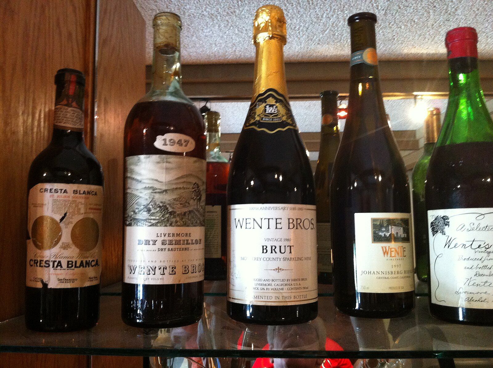 A collection of various wine bottles displayed on a shelf indoors. - Livermore Century Ride