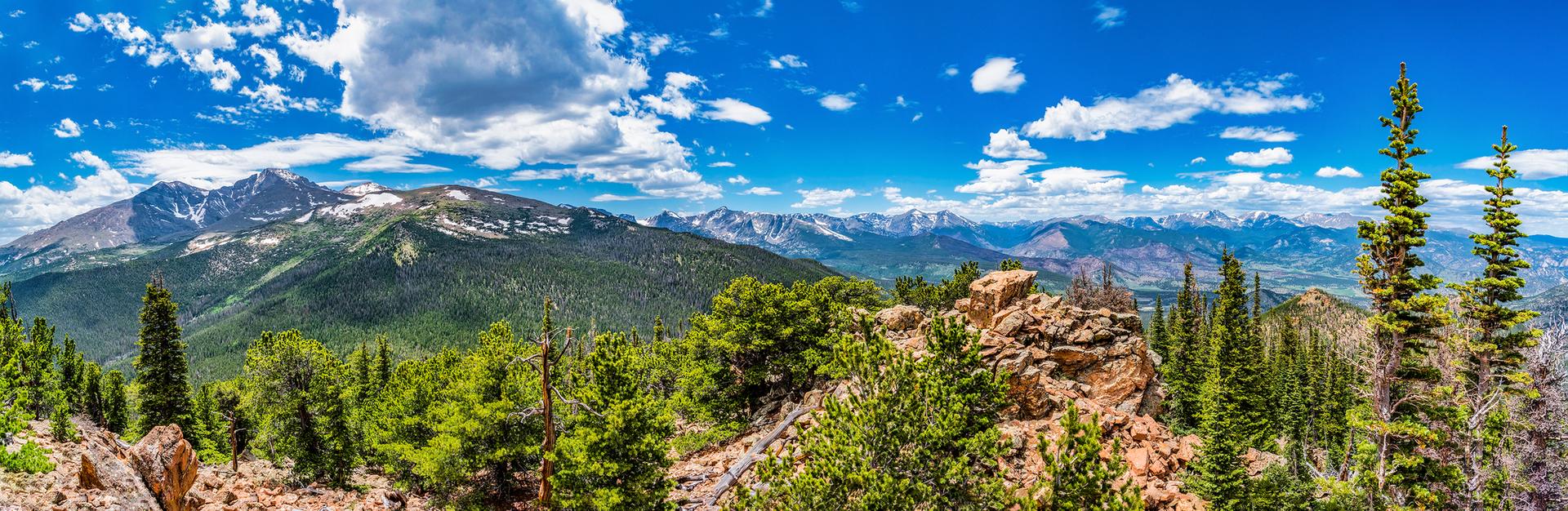 Panoramic view of distant snow-capped mountains under a blue, cloudy sky.