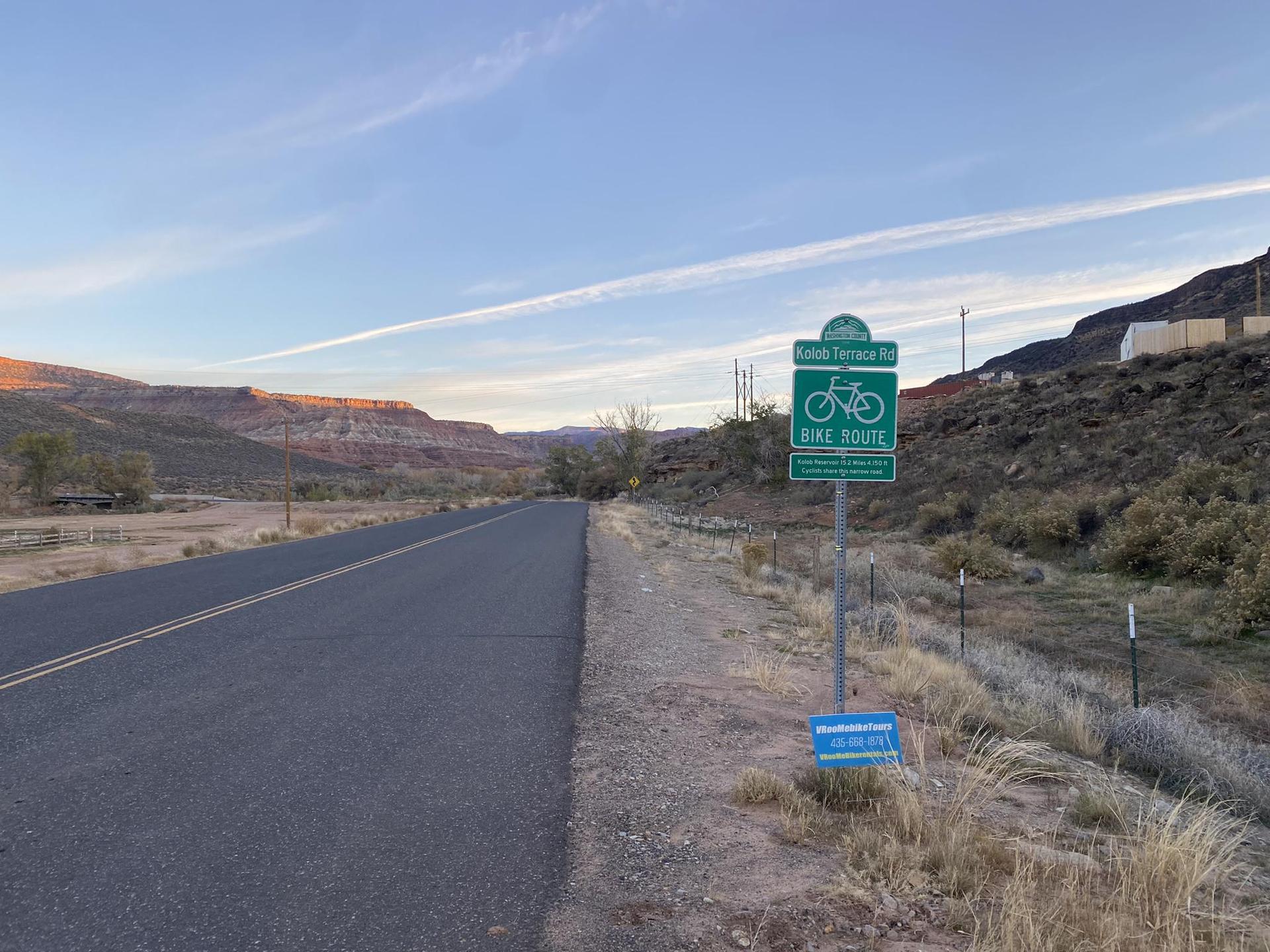 Paved road next to a bike route sign in a desert landscape.