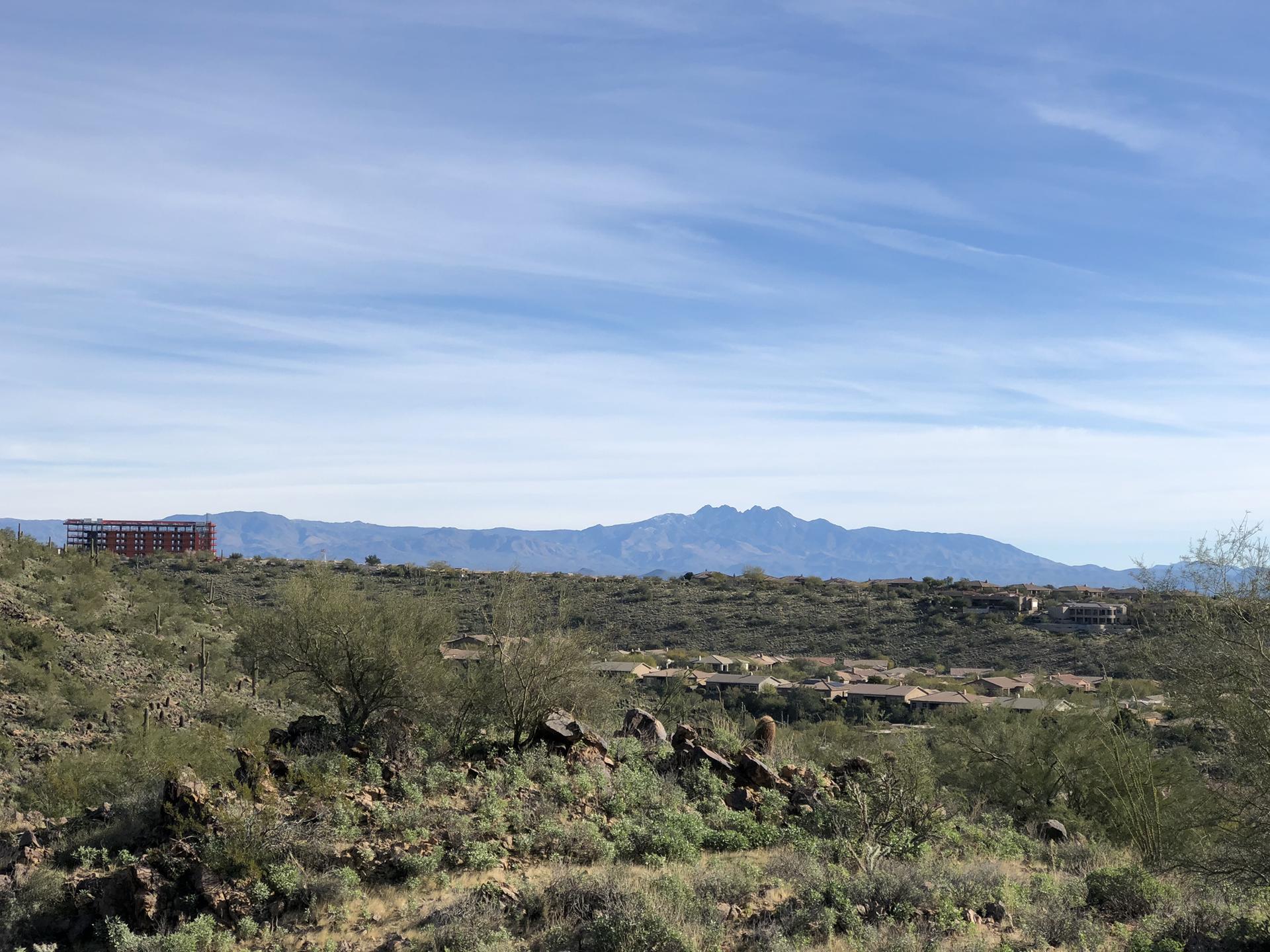 Vast desert landscape with distant mountains, sparse vegetation, and a construction site.