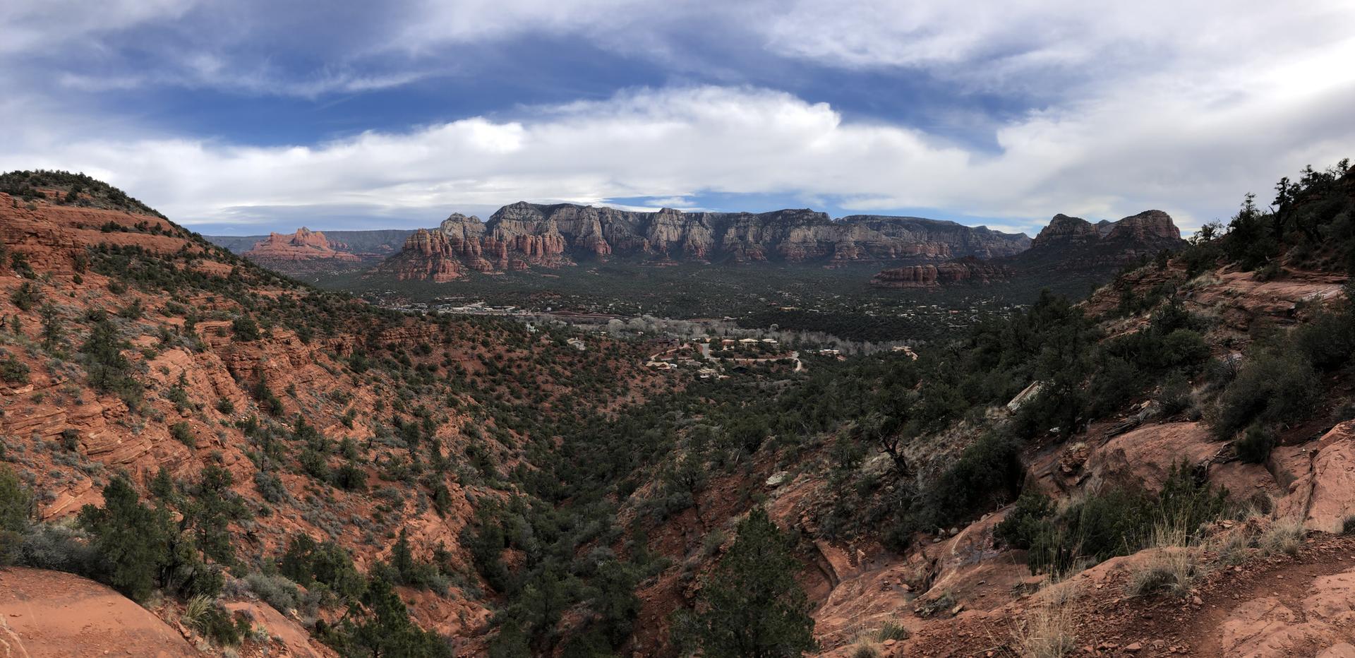 Panoramic view of a town nestled in a valley surrounded by red rock mountains.