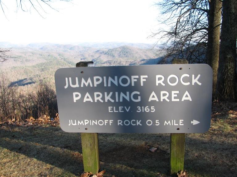 A dark sign on wooden posts, with distant mountains and bare trees.