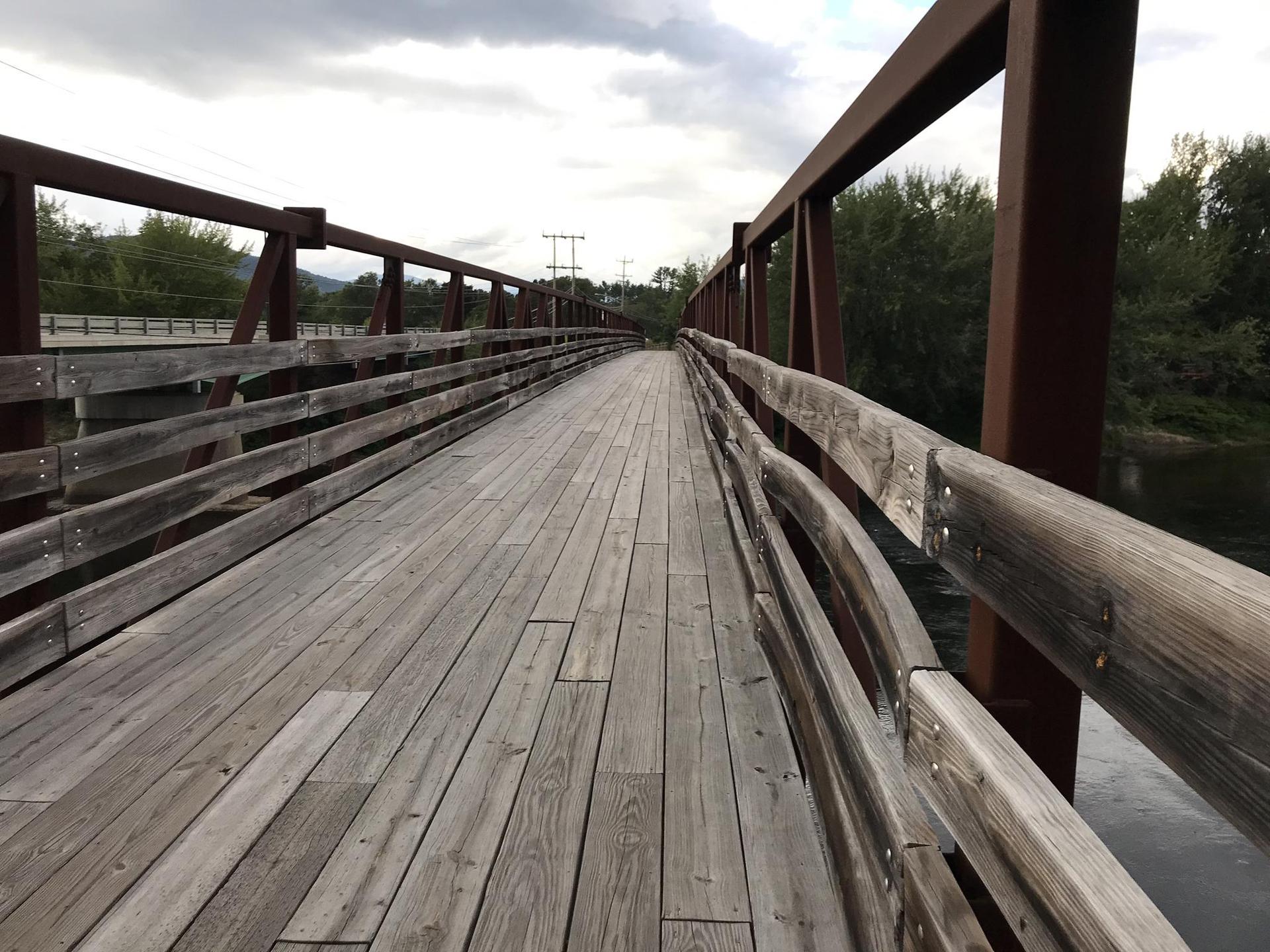 Long wooden bridge with metal railings under an overcast sky.