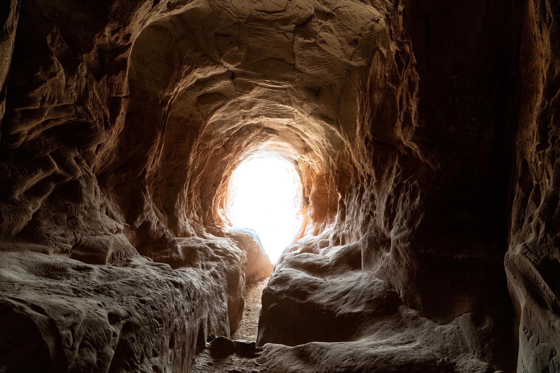 Dark cave interior with a bright, oval opening at the end.