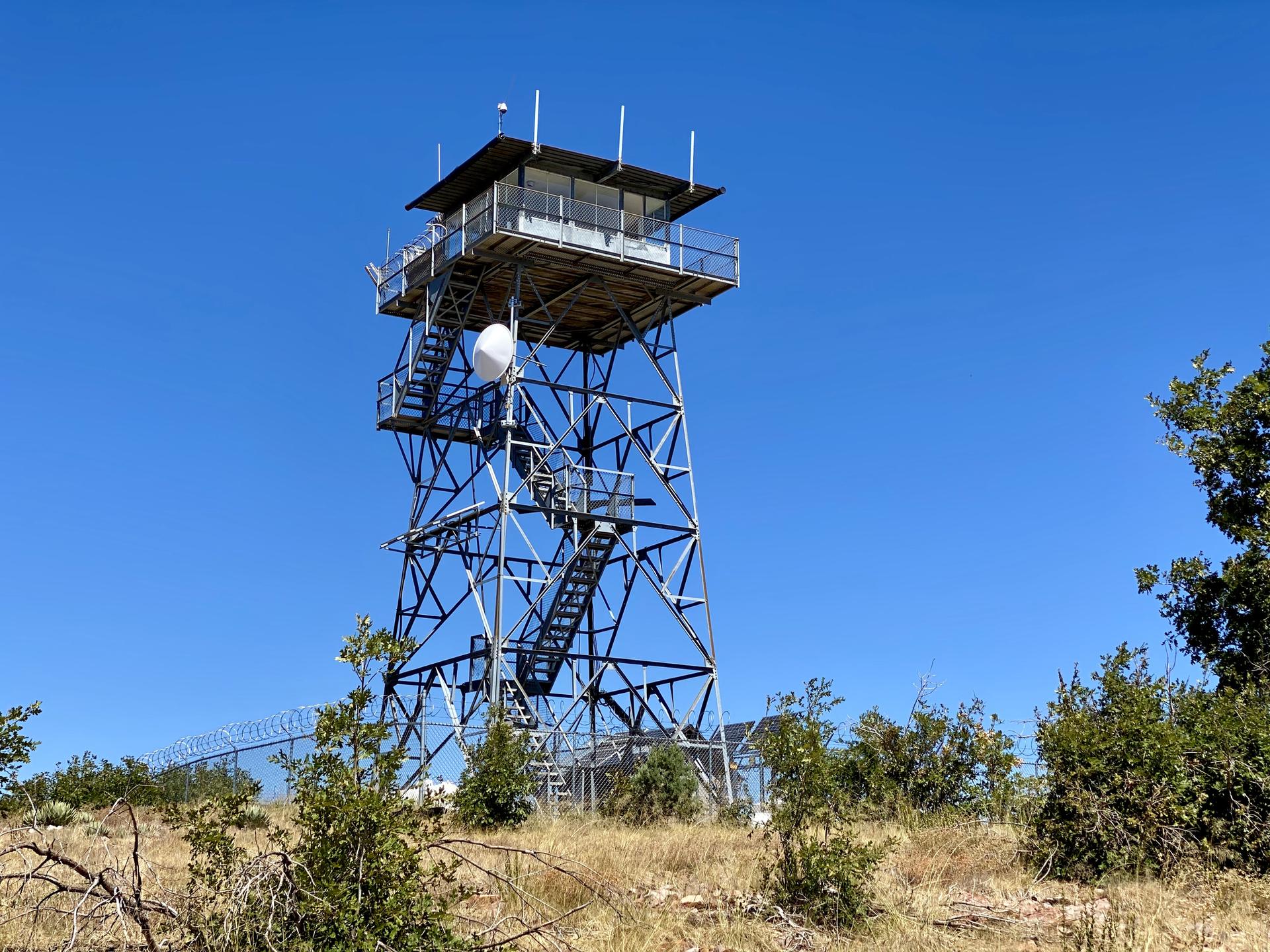 Tall metal fire lookout tower against a clear blue sky.