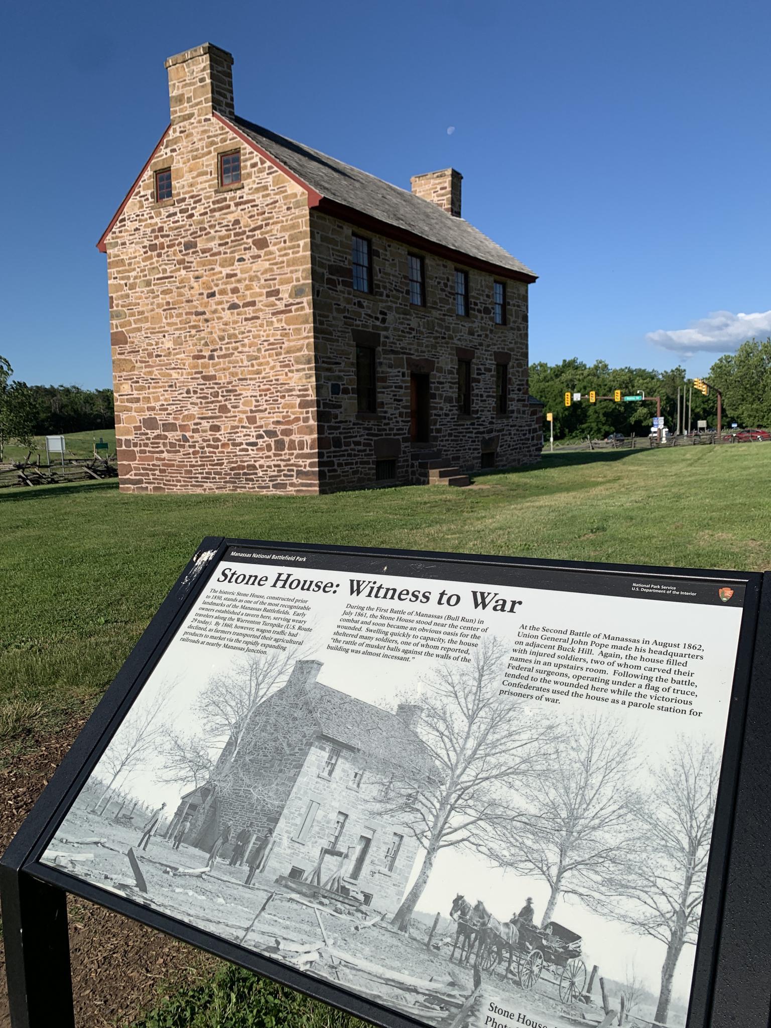 Stone house and an interpretive sign on a sunny day.