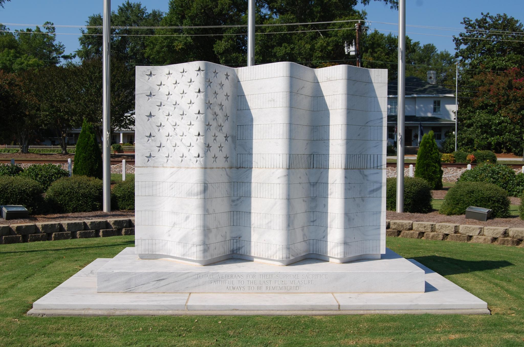 Large white marble monument resembling a flag on a sunny day.