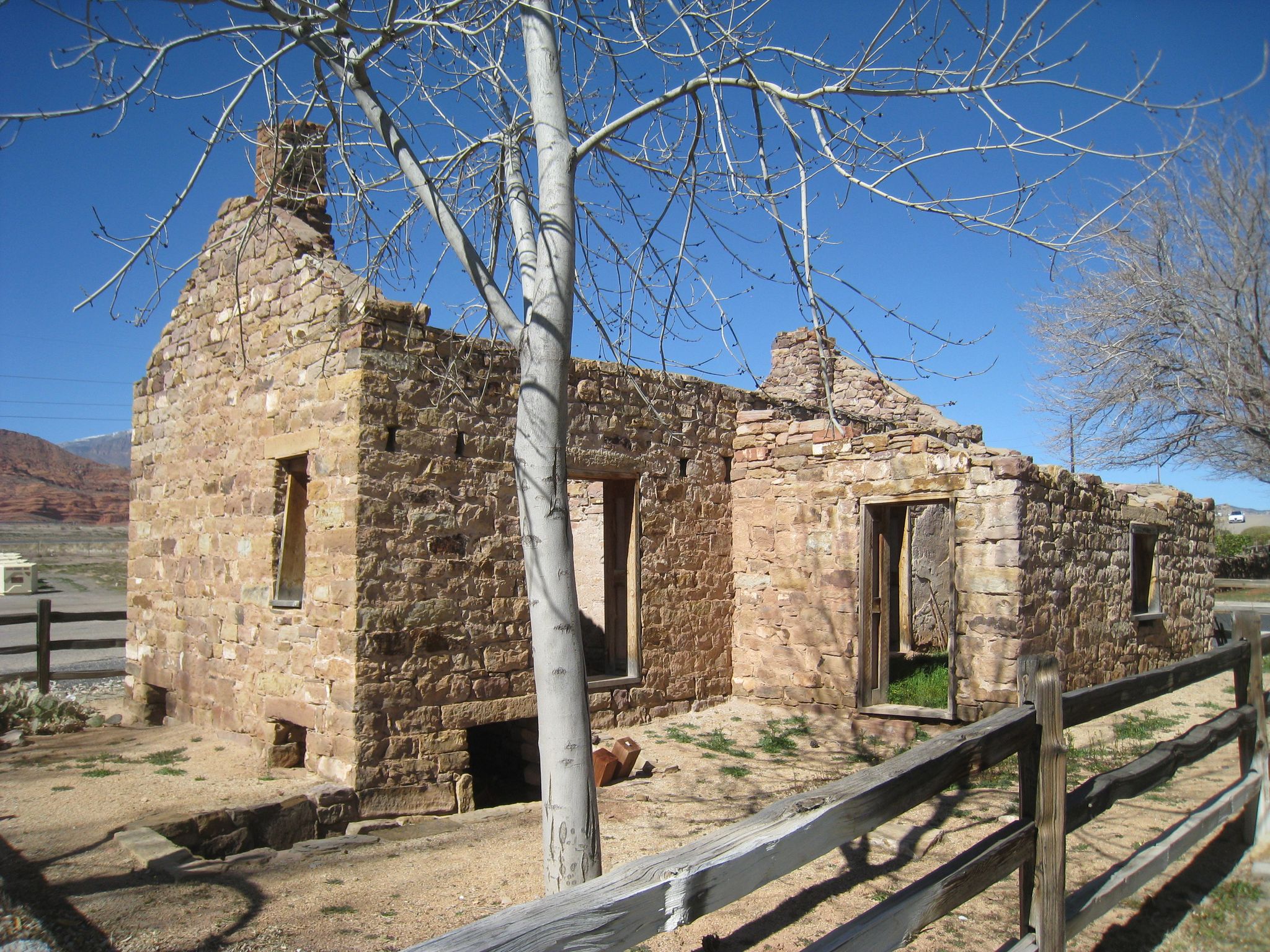 Sunlit ruins of a stone building with bare trees and a clear blue sky. - Harrisburg Ghost Town Ruins – Quail Creek Reservoir loop from Harrisburg