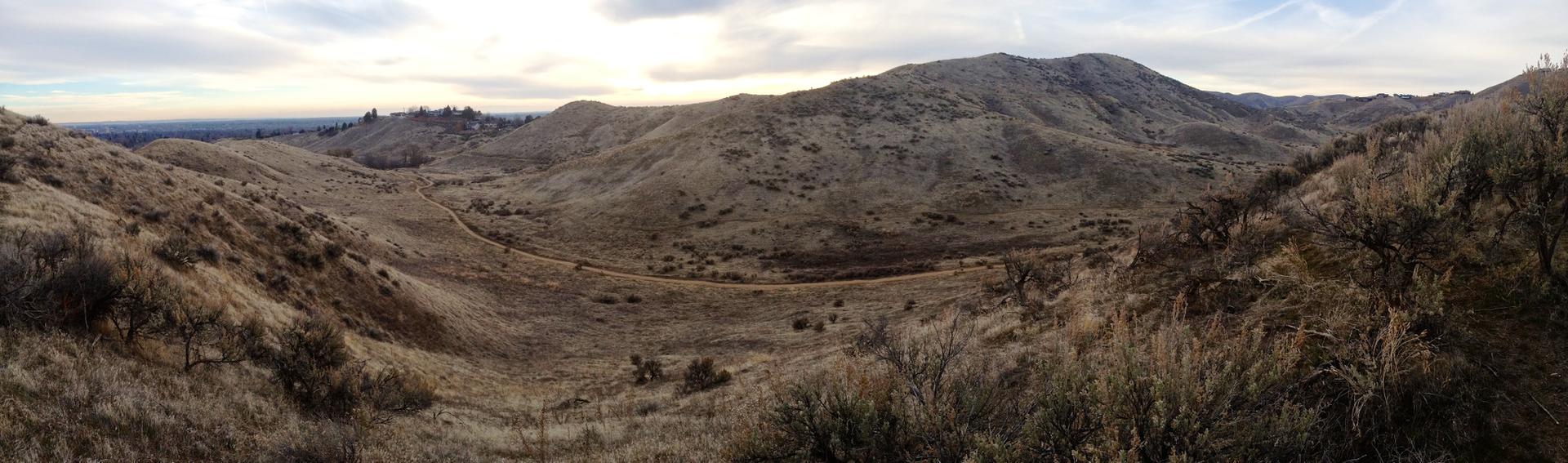 Panoramic view of dry, rolling hills and valleys under an overcast sky.