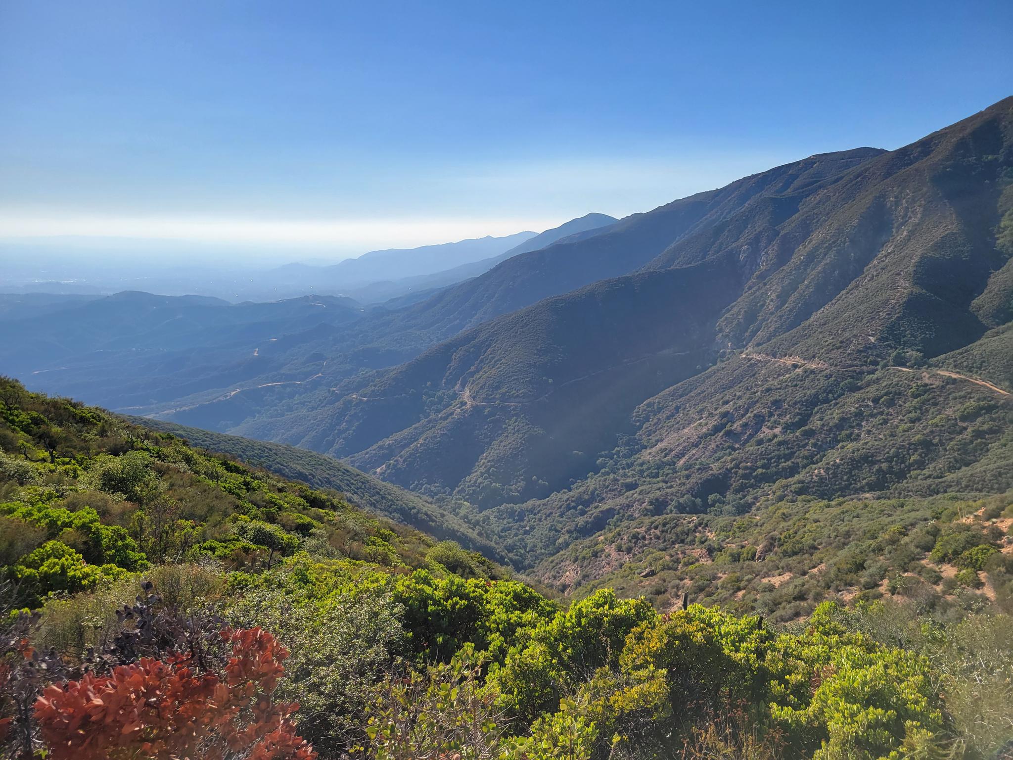 Vast mountainous landscape with deep valleys under a clear blue sky.