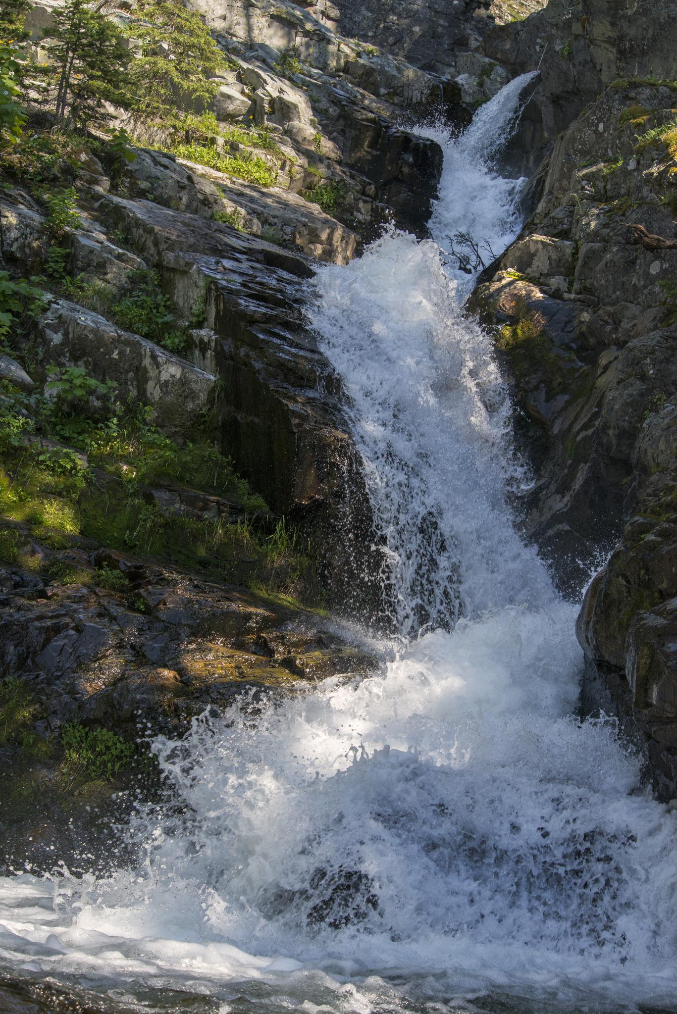 Powerful waterfall cascading down rocky cliffs into a pool below.