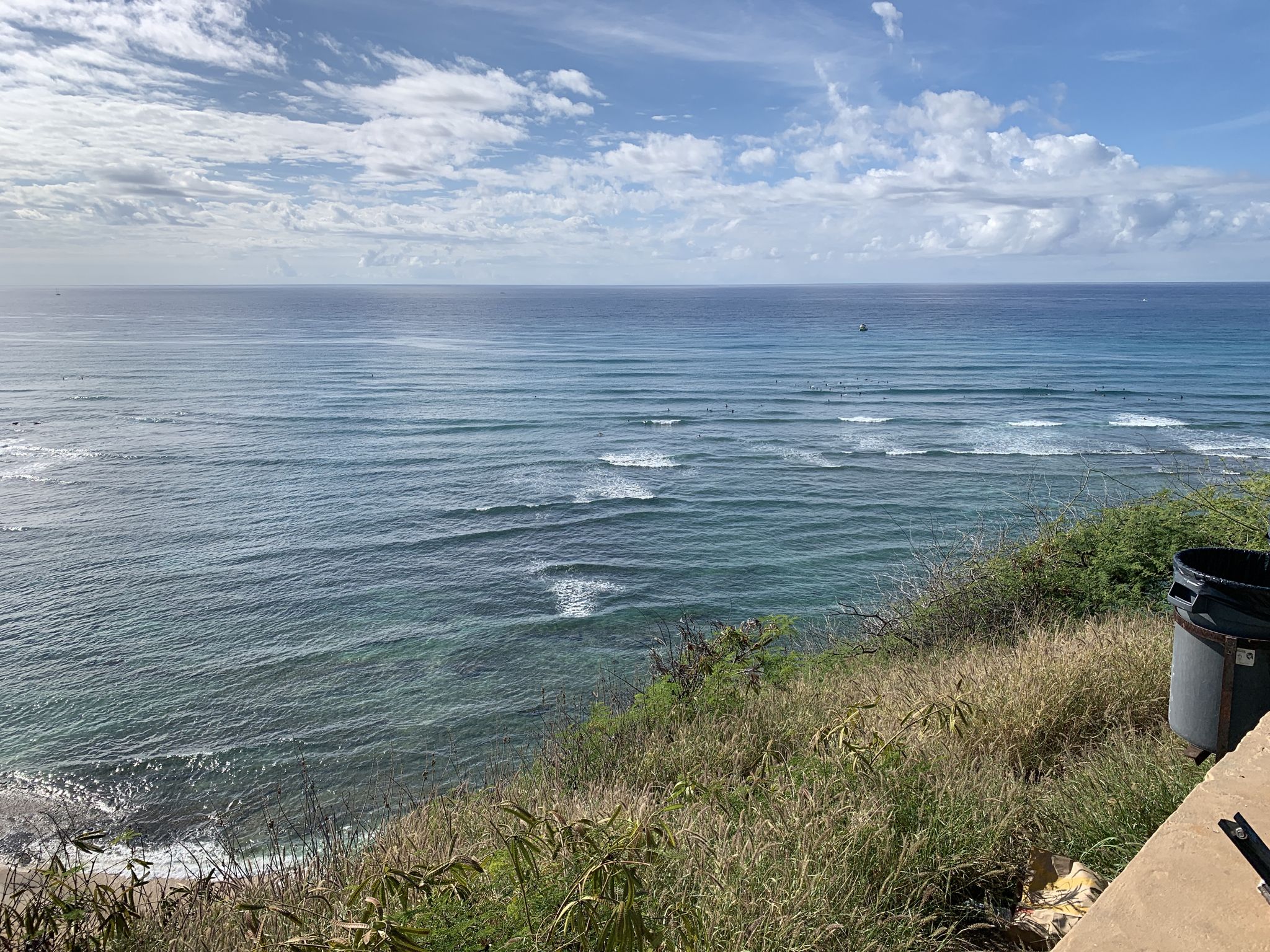 Wide ocean view with gentle waves, a grassy cliff, and cloudy sky. - Waikiki to Wai‘alae Beach Park loop via Kahala Avenue