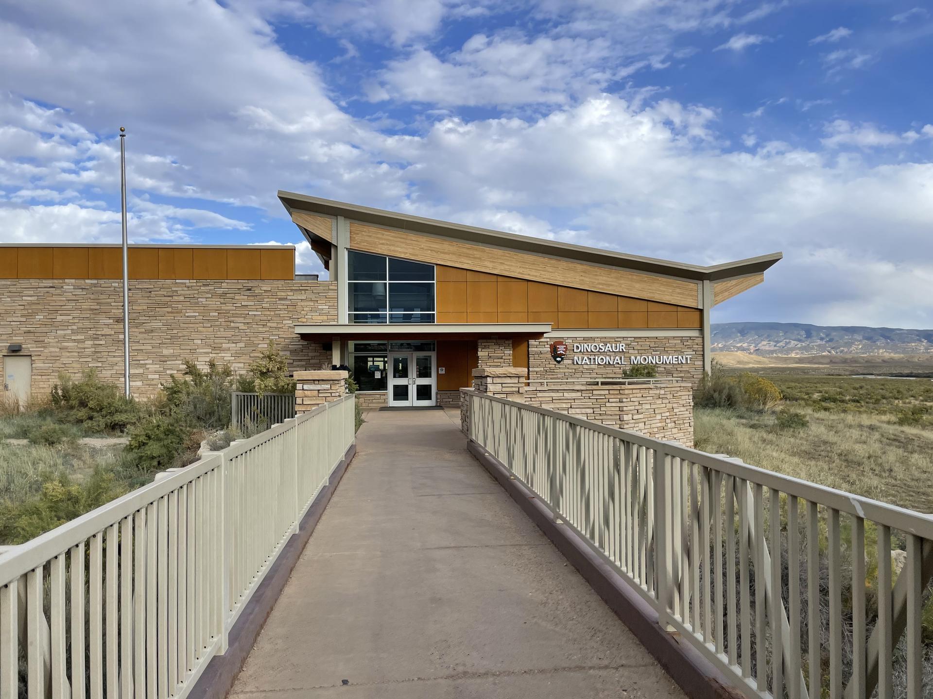 A modern building with a sloped roof and a long ramp under a blue sky.
