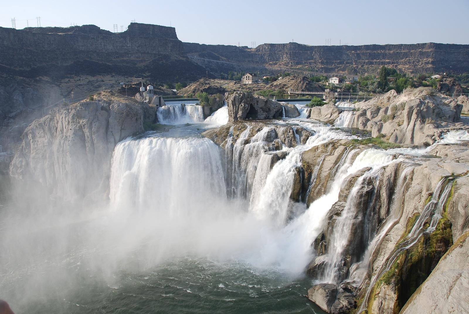 Powerful waterfalls cascade into a river, surrounded by rocky cliffs.