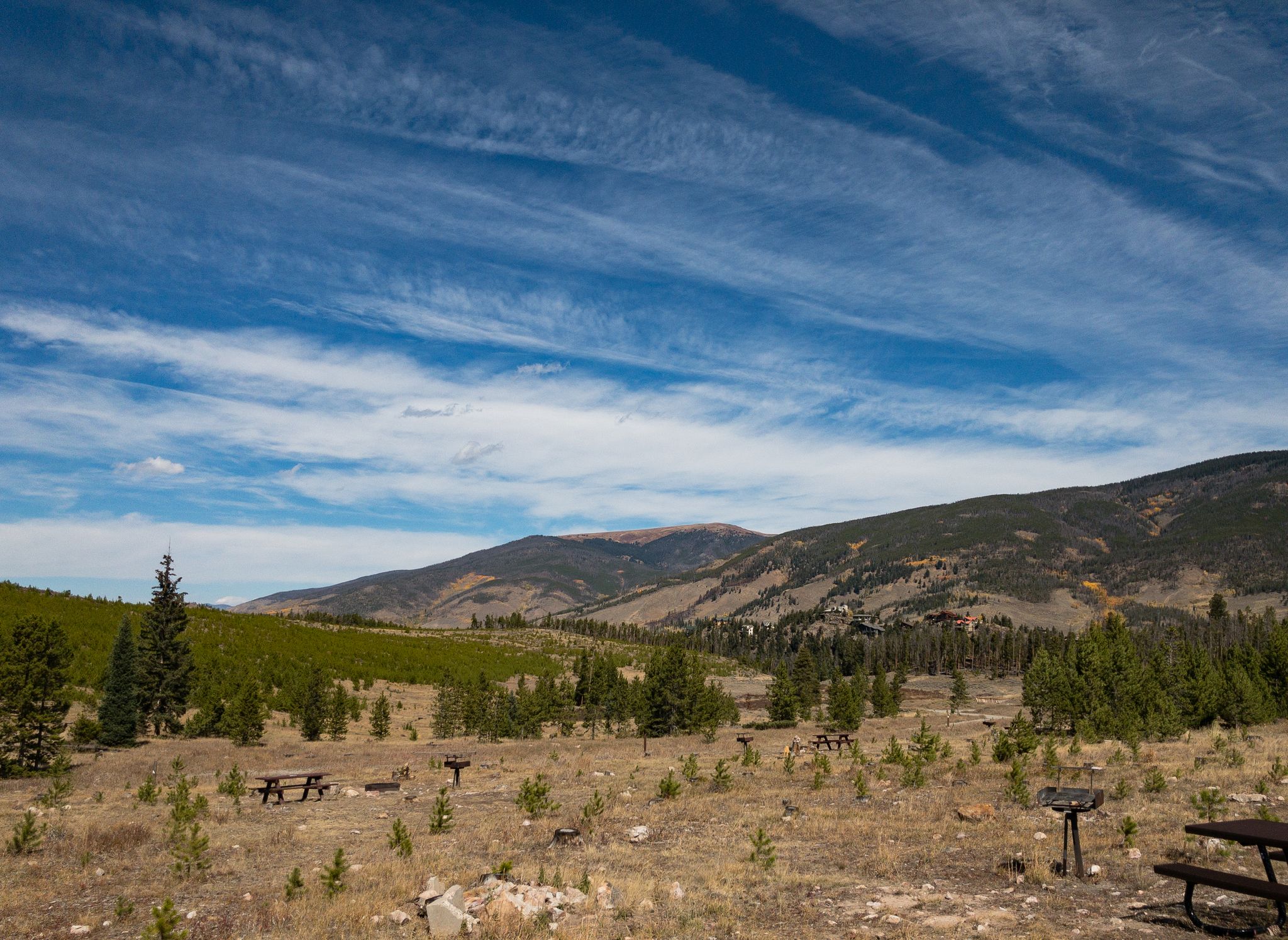 A wide-angle view of a picnic area with mountains and a blue sky. - Windy Point via Prospector Camp