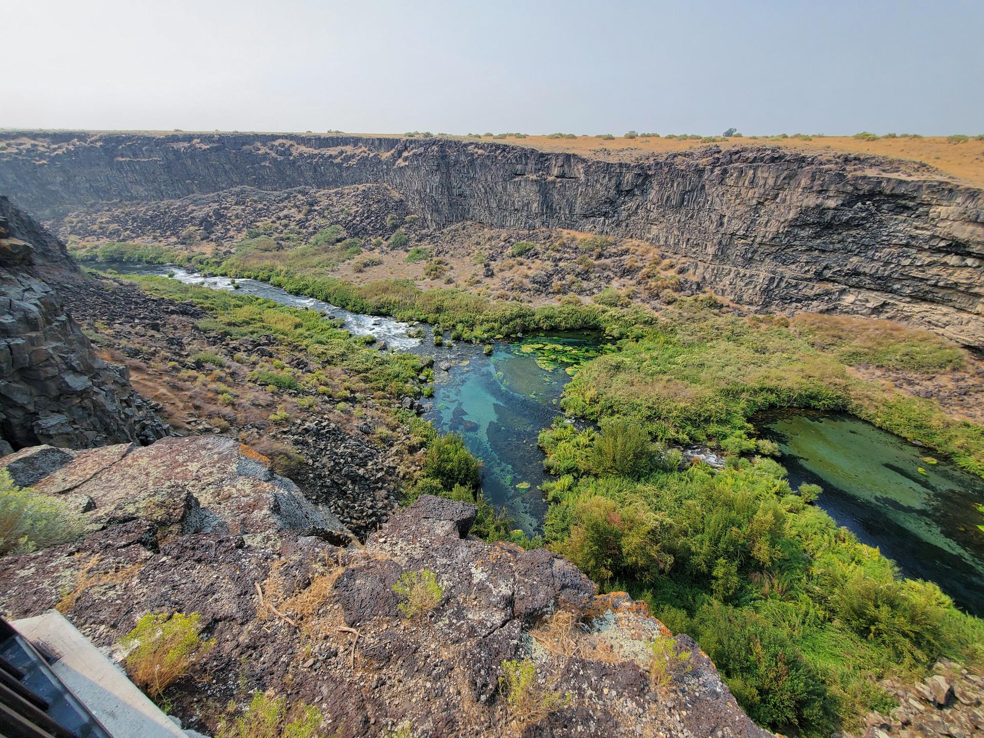 Aerial view of a winding river in a deep canyon with rocky walls.