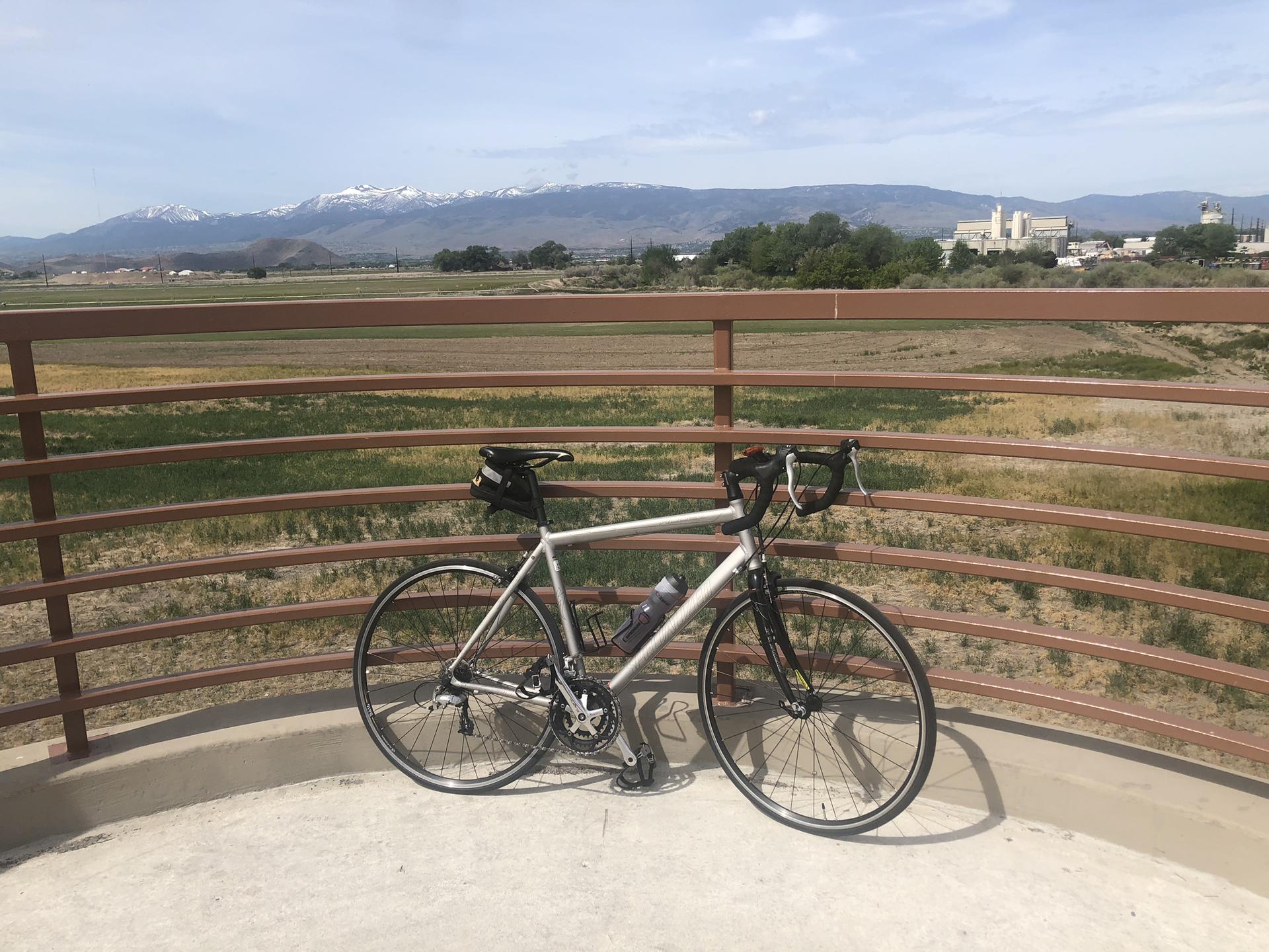 A bicycle rests on a platform overlooking distant mountains and buildings.