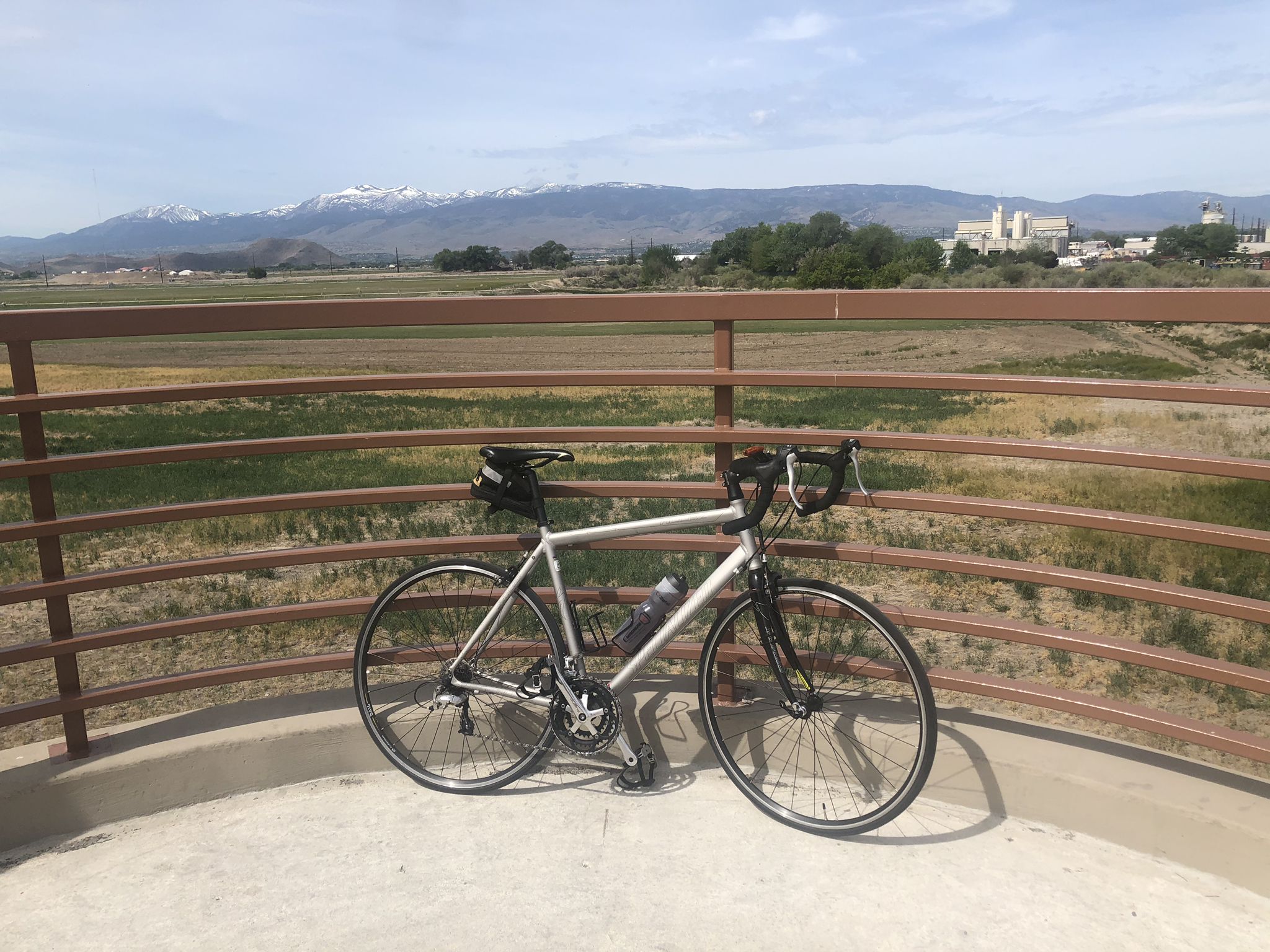 A bicycle rests on a platform overlooking distant mountains and buildings. - Erica Greif Memorial Bikeway