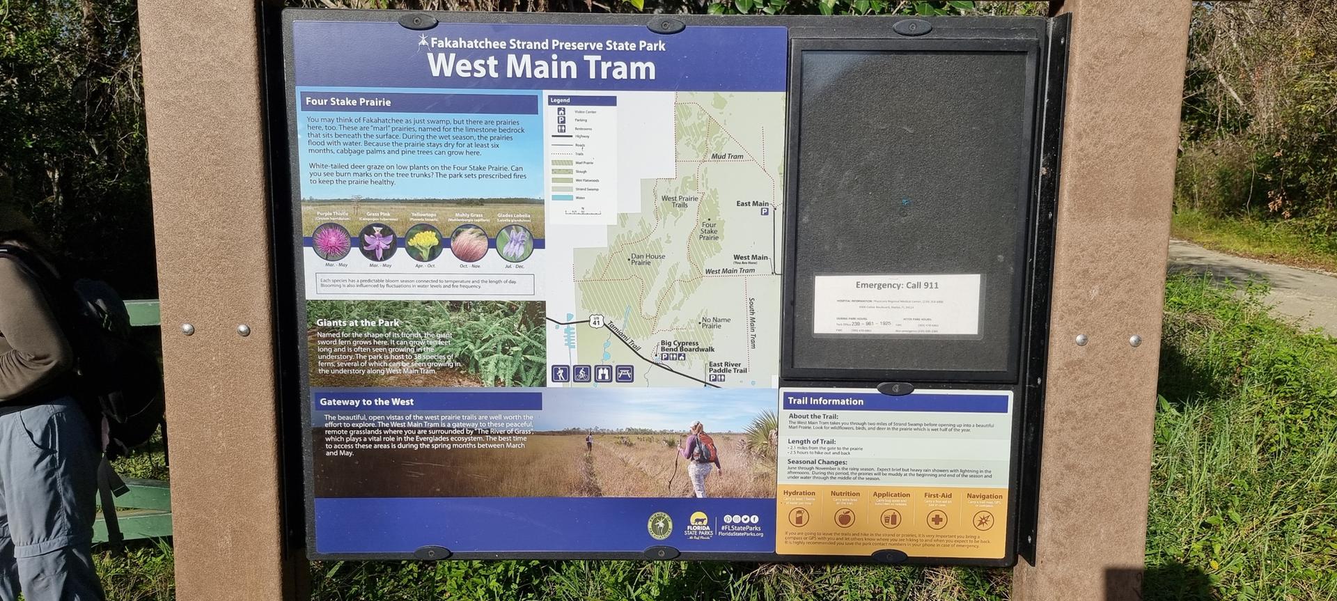 An outdoor information board stands beside a path on a bright day.