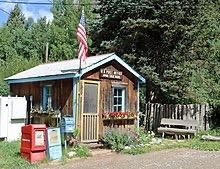 Brightly lit rustic cabin with an American flag and flower boxes.