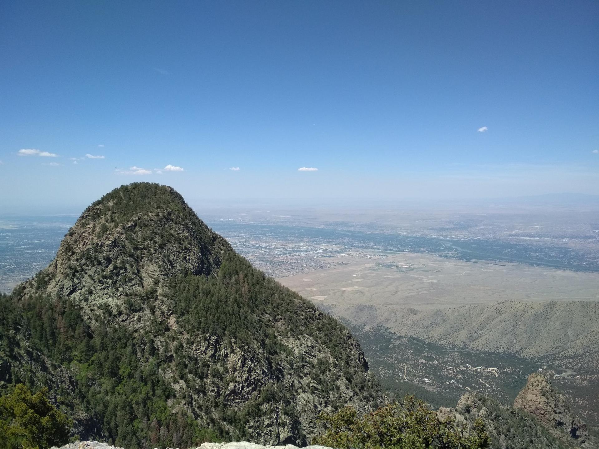 A prominent, green mountain peak overlooking a vast valley.