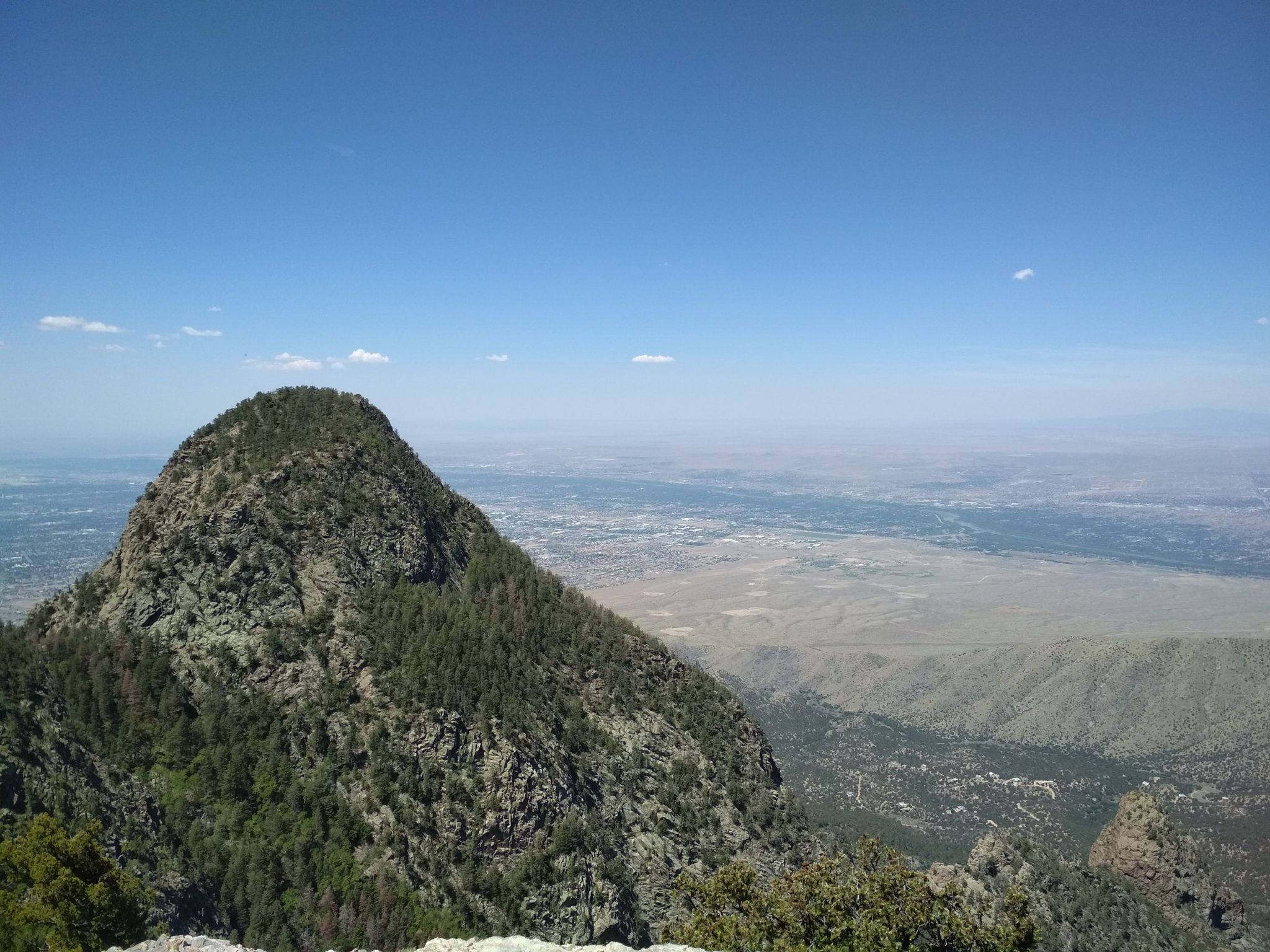 A prominent, green mountain peak overlooking a vast valley. - North Crest Trail