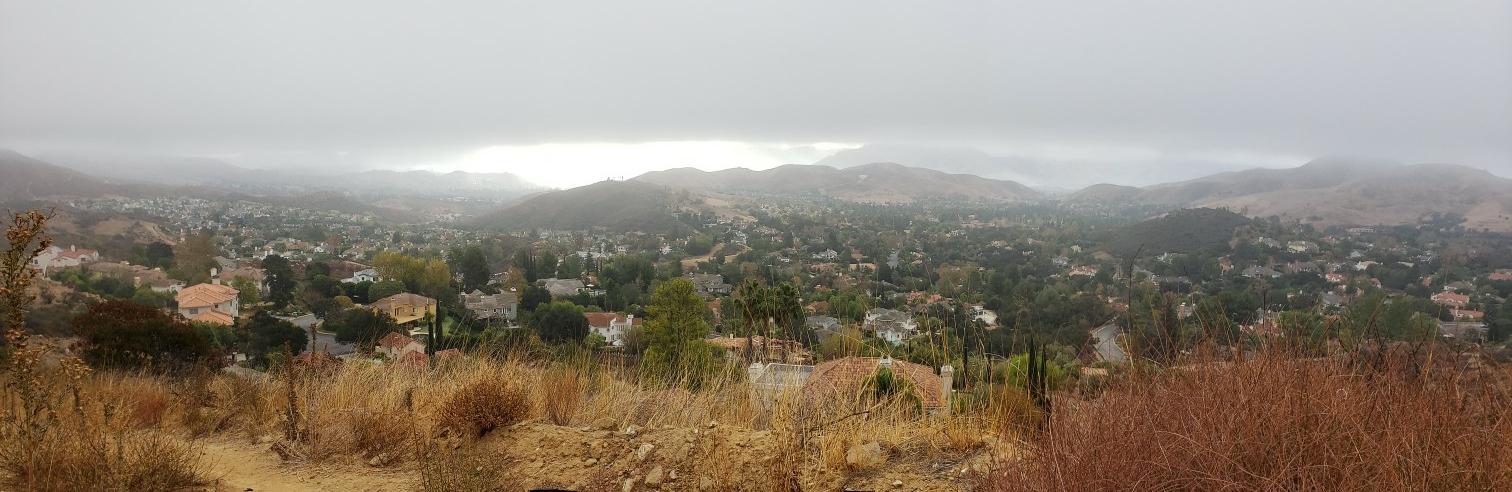 Wide view of a residential valley under a heavy, cloudy, gray sky.