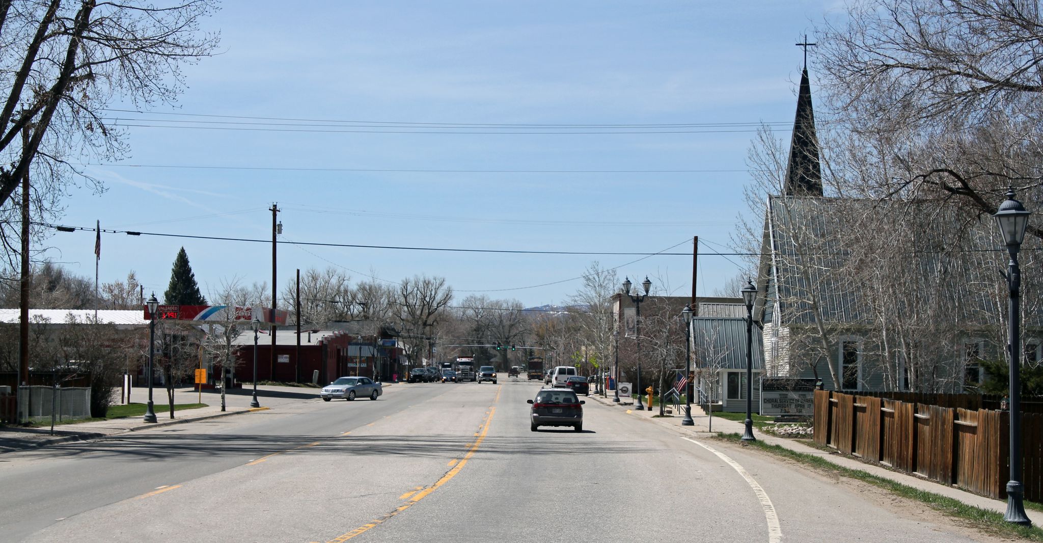 A sunny street scene with cars, buildings, bare trees, and a church steeple. - Hayden loop from Hayden