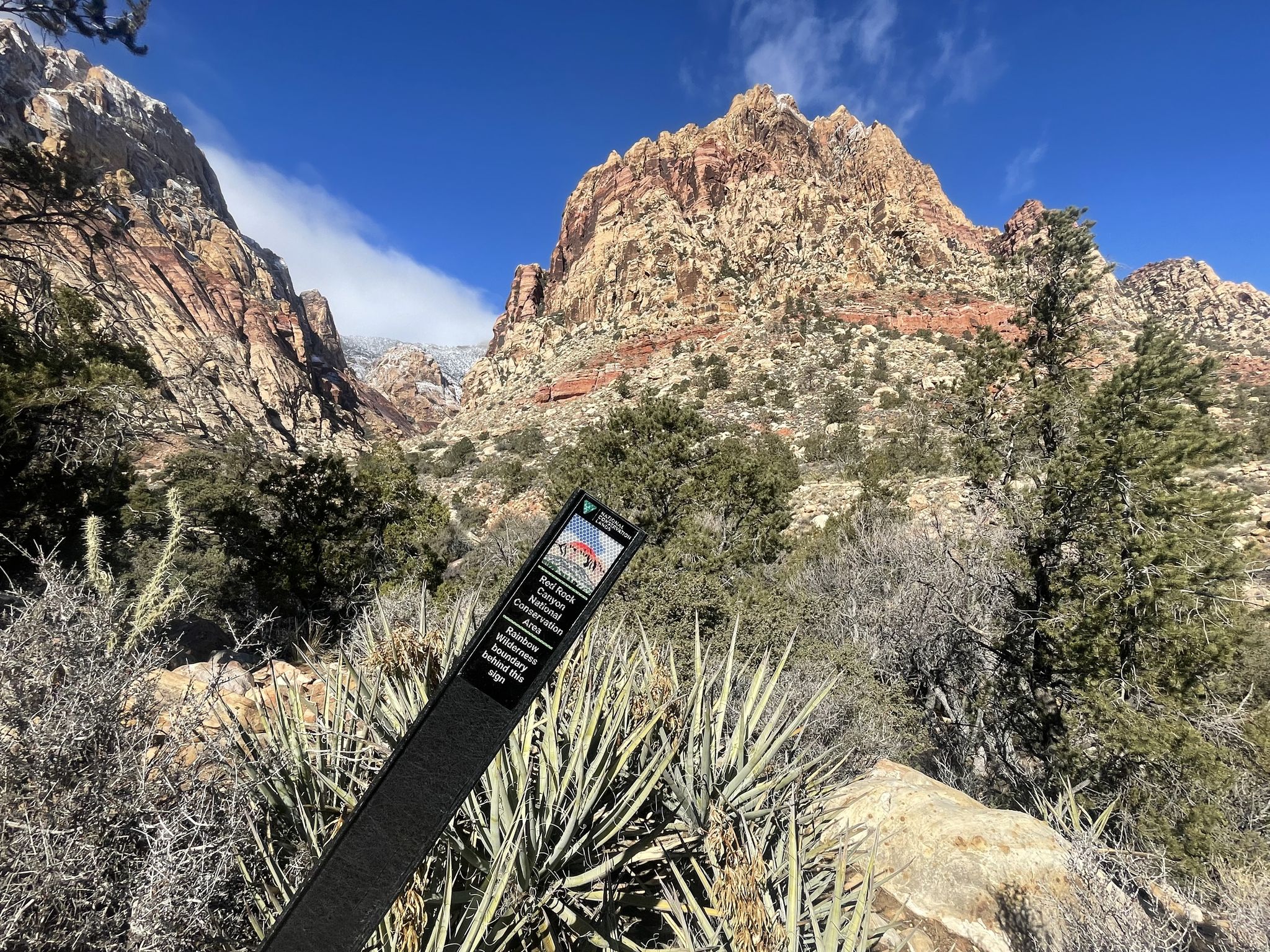 Informational sign in a desert landscape with large red rock mountains. - First Creek Canyon Trail