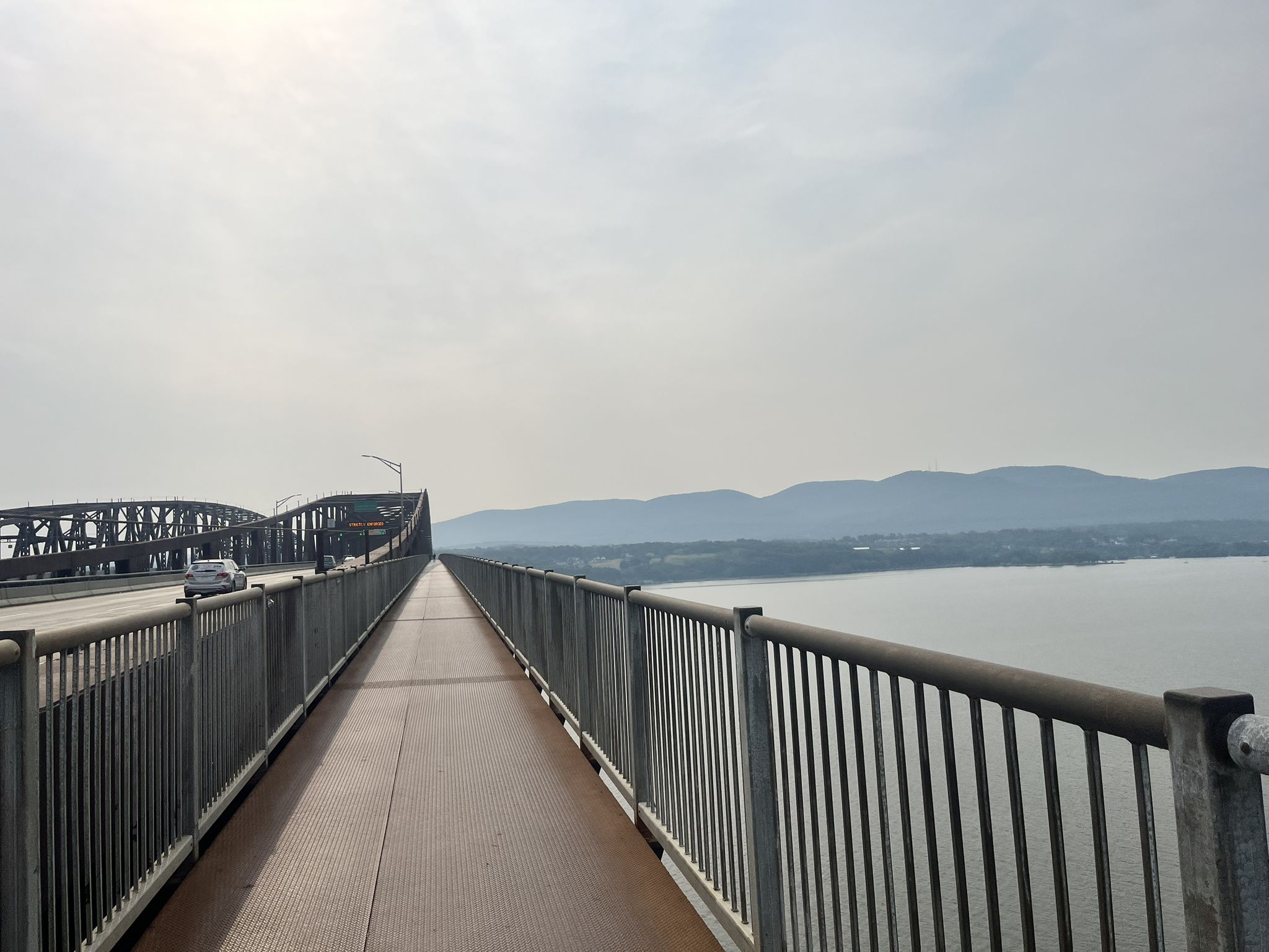 Long bridge with pedestrian walkway and vehicle lanes over water, hazy sky. - Newburgh-Beacon Bridge loop from Newburgh