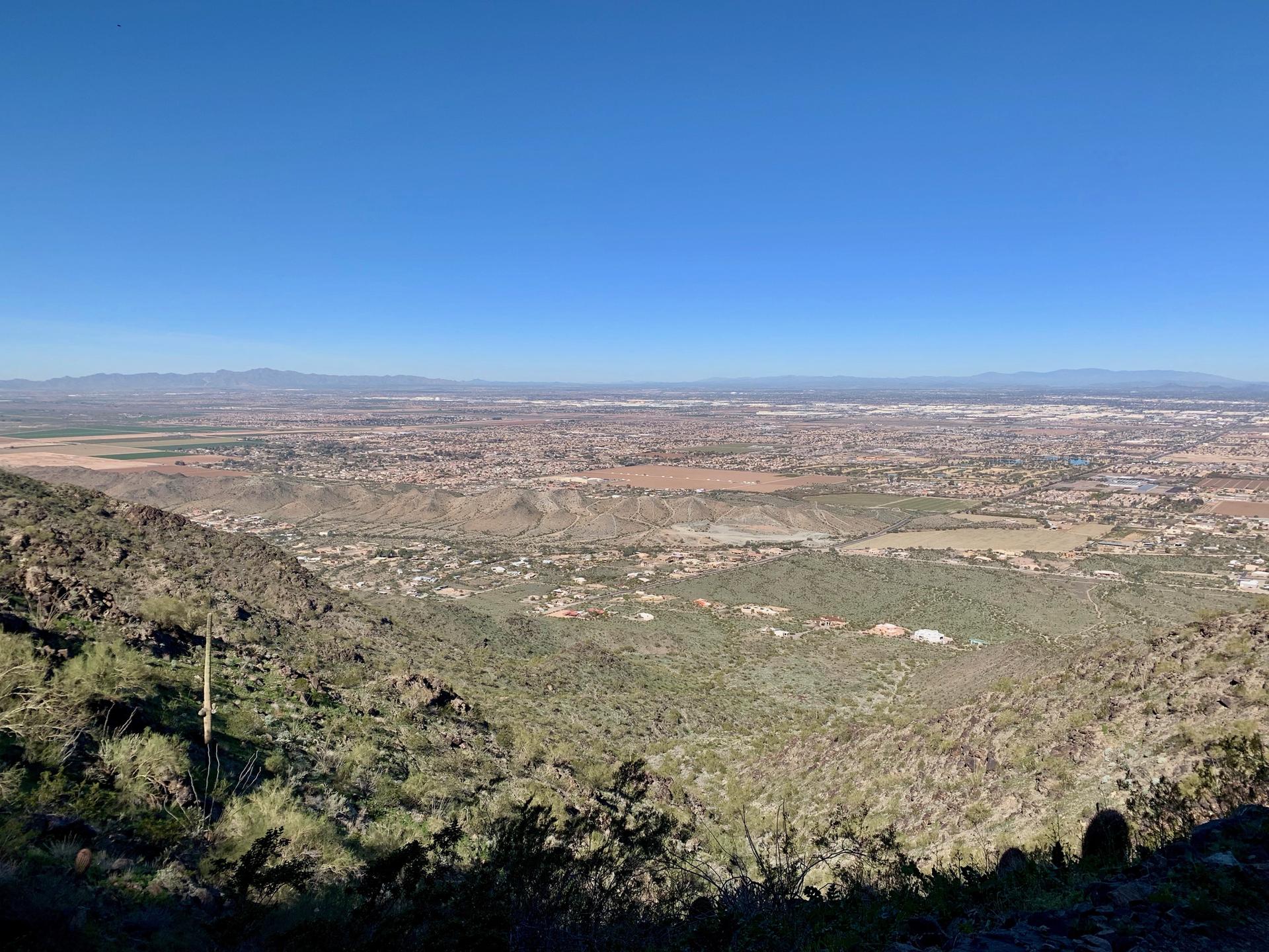 Expansive panoramic view of a sprawling city and distant mountains under clear blue sky.